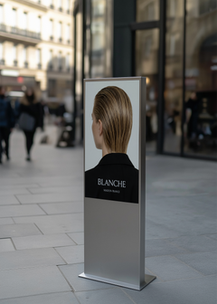 Street totem sign mockup displaying editorial fashion campaign image and serif brand name, Parisian boulevard setting