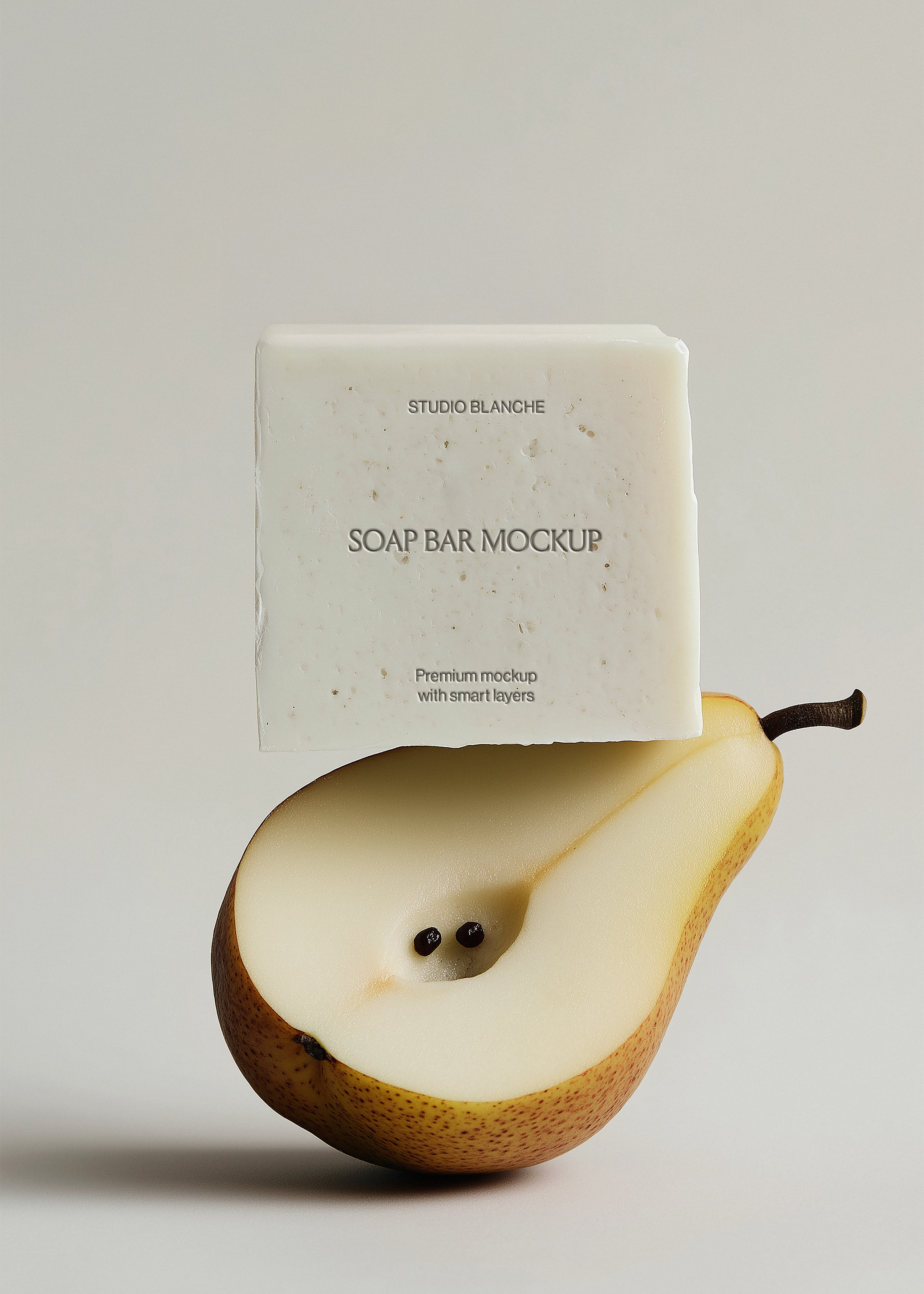 White soap bar mockup resting on sliced pear, Studio Blanche label placeholder, minimal grey backdrop, editorial scene