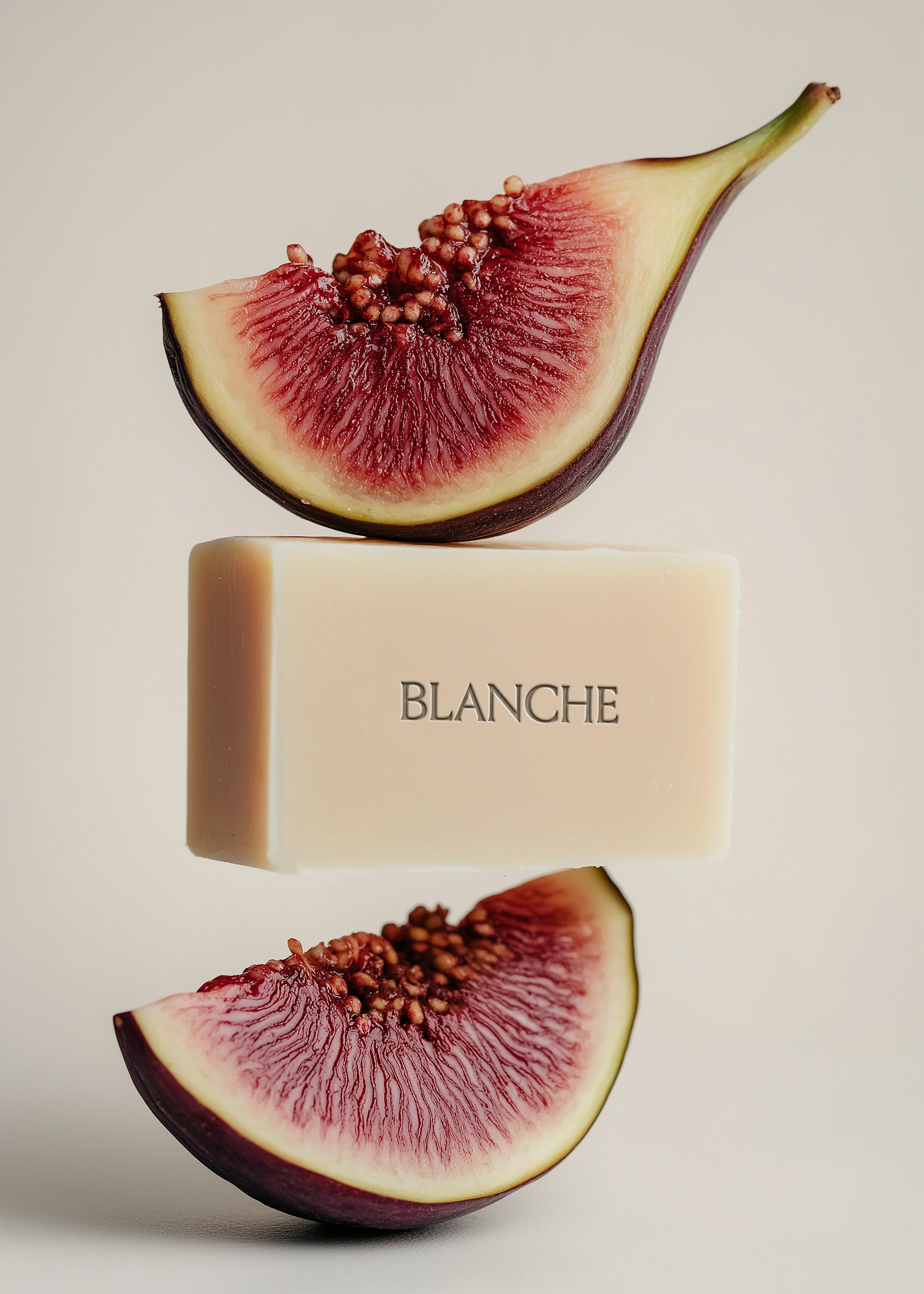 Cream landscape soap bar suspended between two sliced figs with deep crimson interiors, warm grey background, embossed brand label