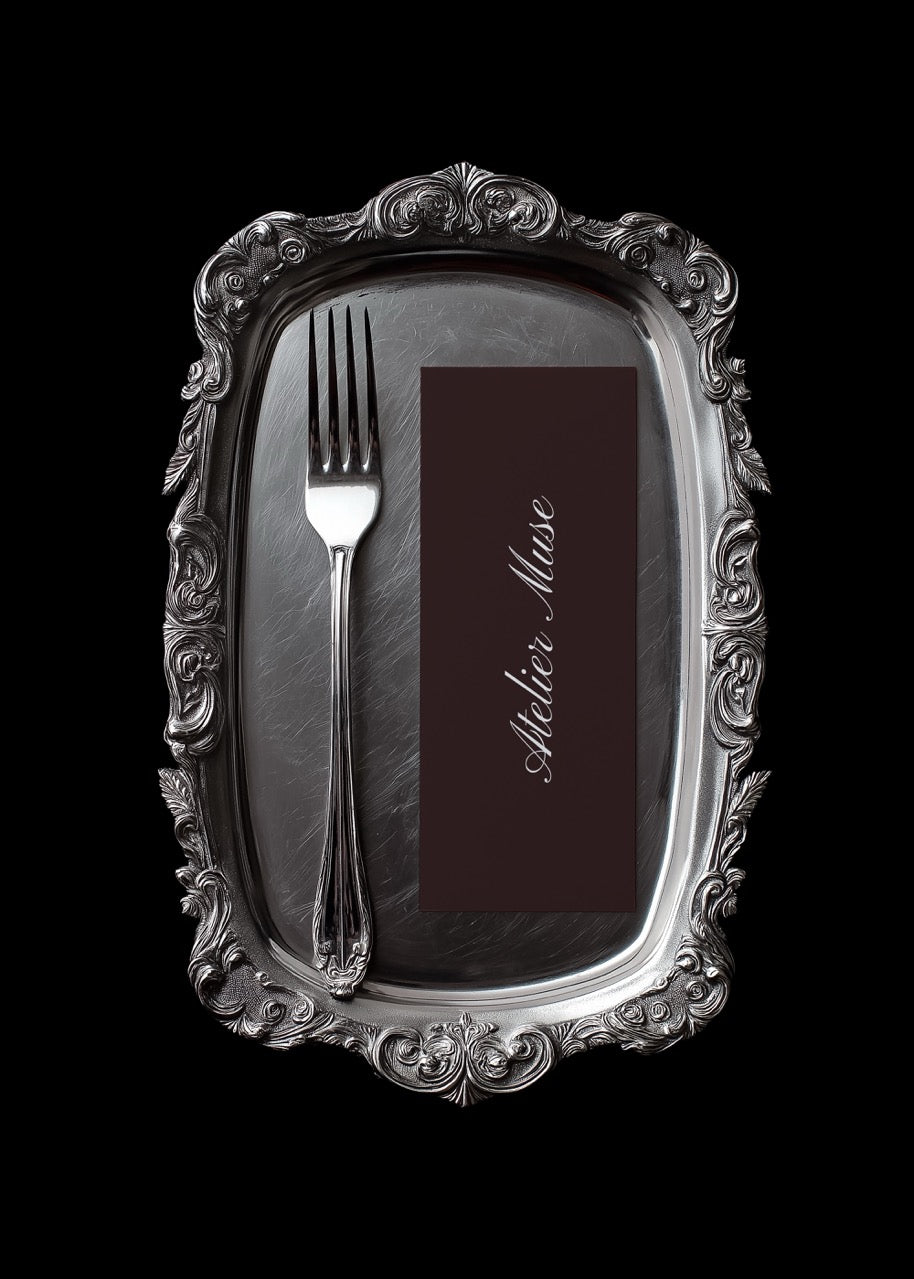 Decorative silver tray with a fork and name card on a black background