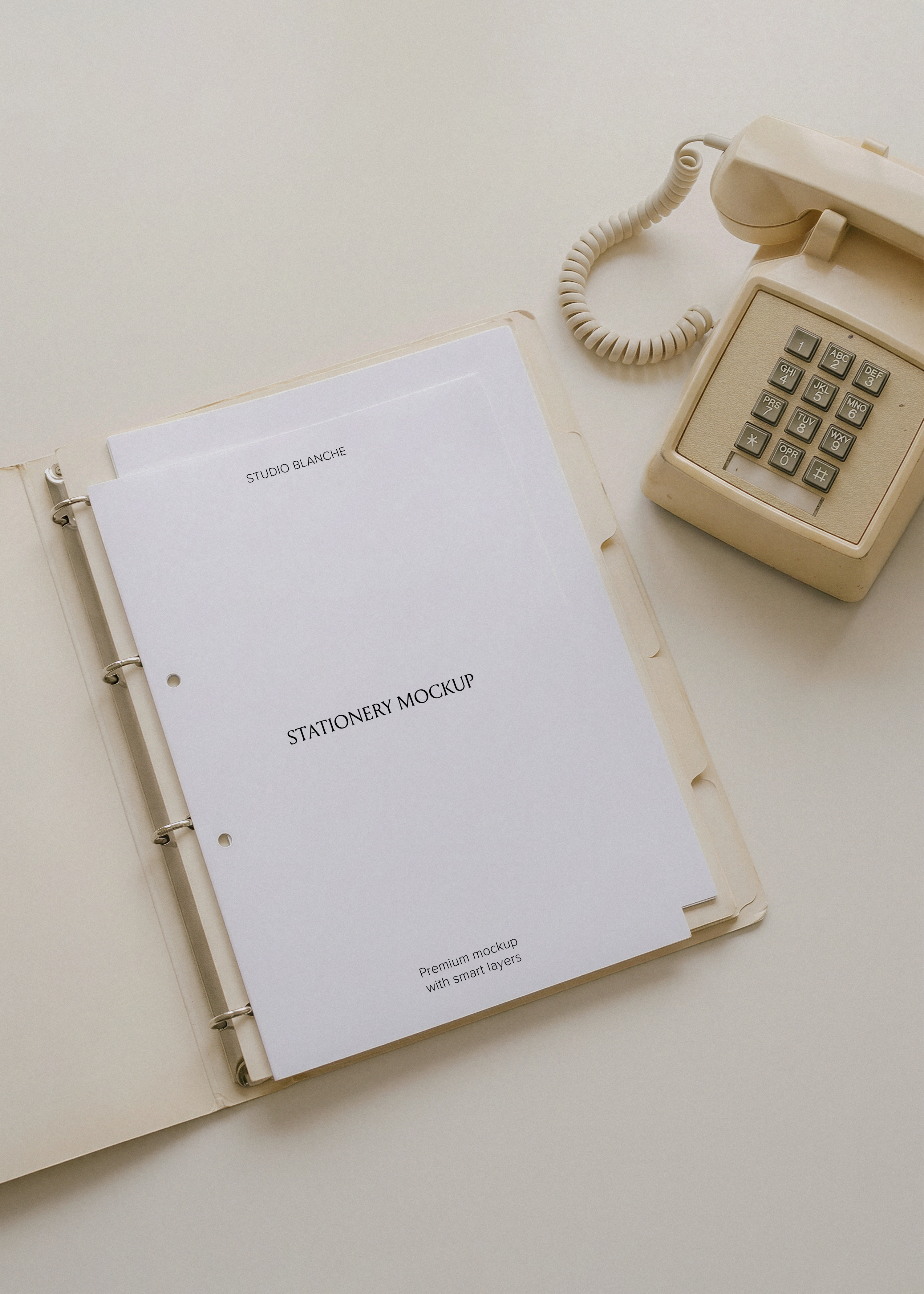 Blank A4 letterhead in open ring binder with cream dividers, retro corded push-button phone on pale desk, flat lay view