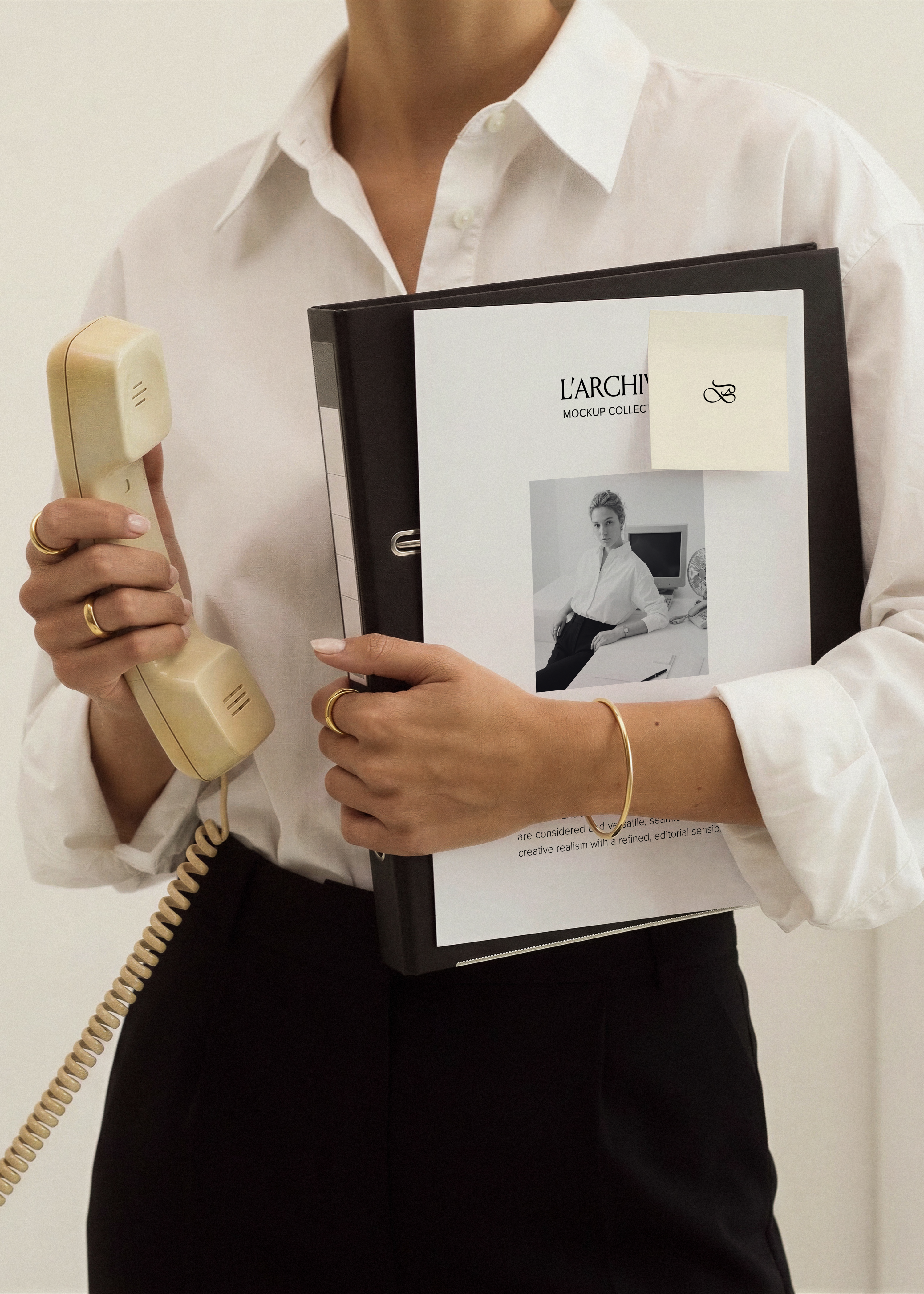 A4 card stationery mockup with sticky note on black binder, held in arm with cream vintage handset, white shirt, gold rings
