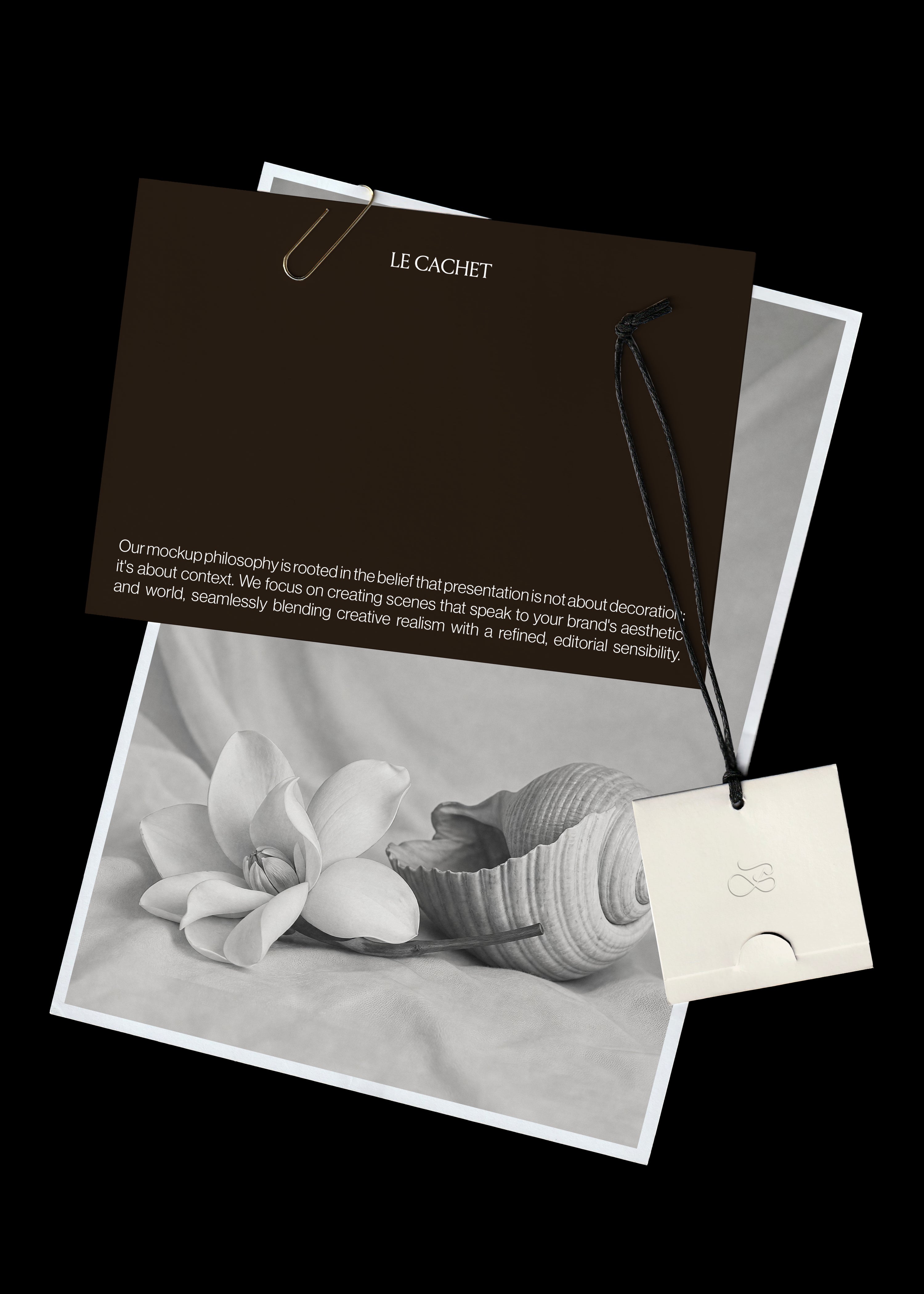 Card, paper and swing tag mockup, dark brown card with gold paperclip over a grey flower and shell print