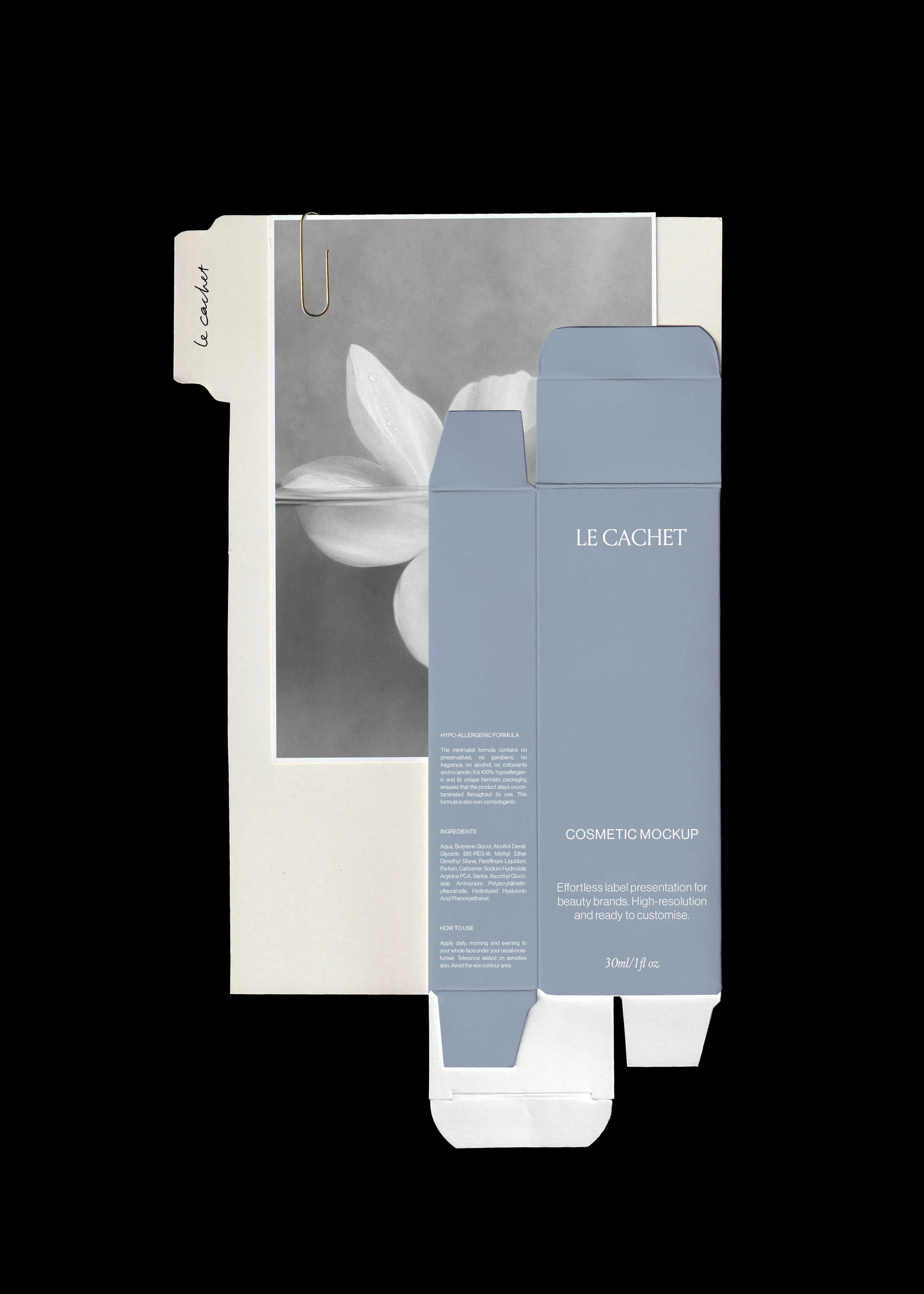 Cosmetic box mockup in dusty blue over a cream tabbed divider and black and white flower print, gold paperclip