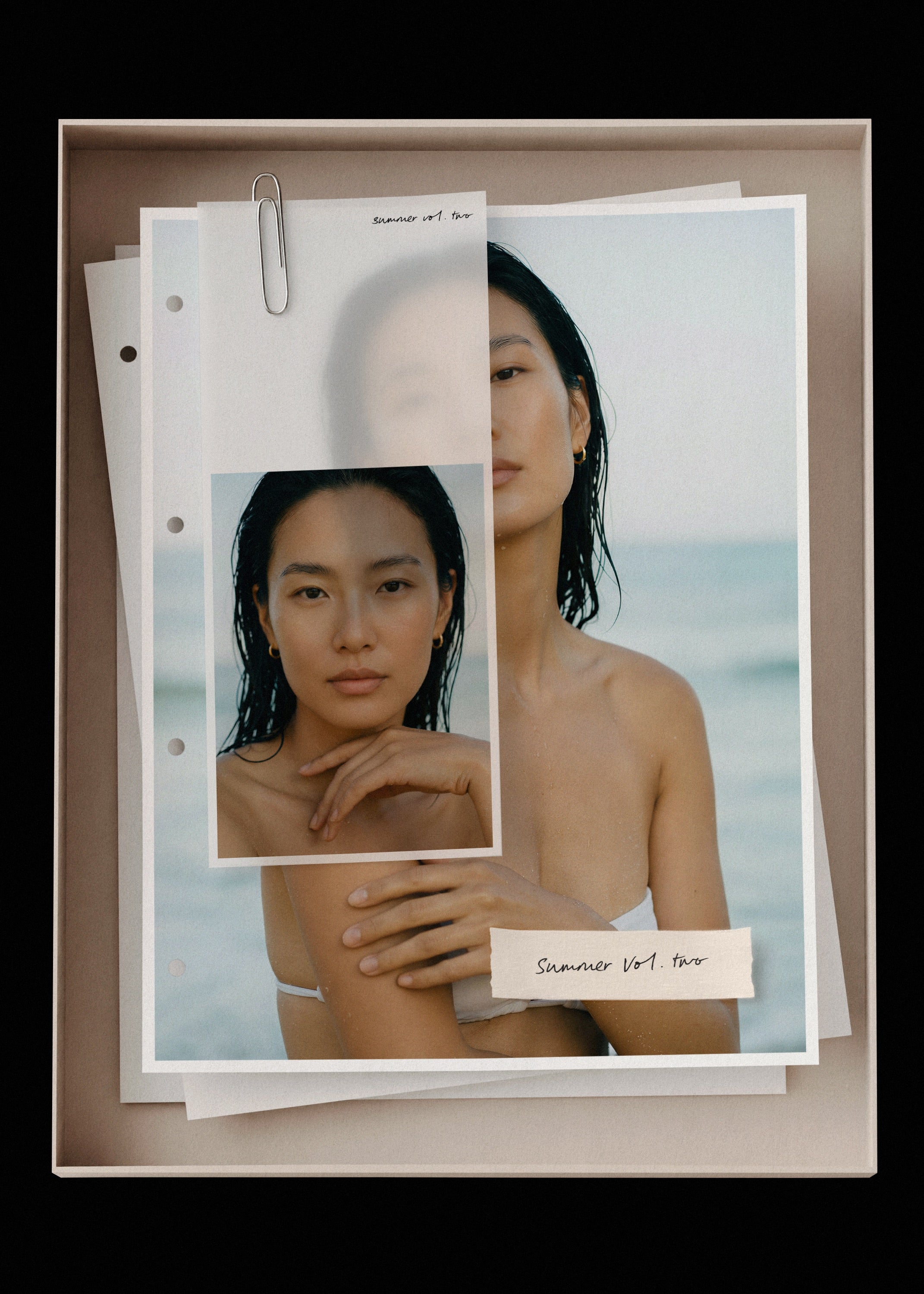 Summer Vol. Two mockup, layered prints in sand box, dark-haired model with wet hair, cool ocean tones, Studio Blanche.
