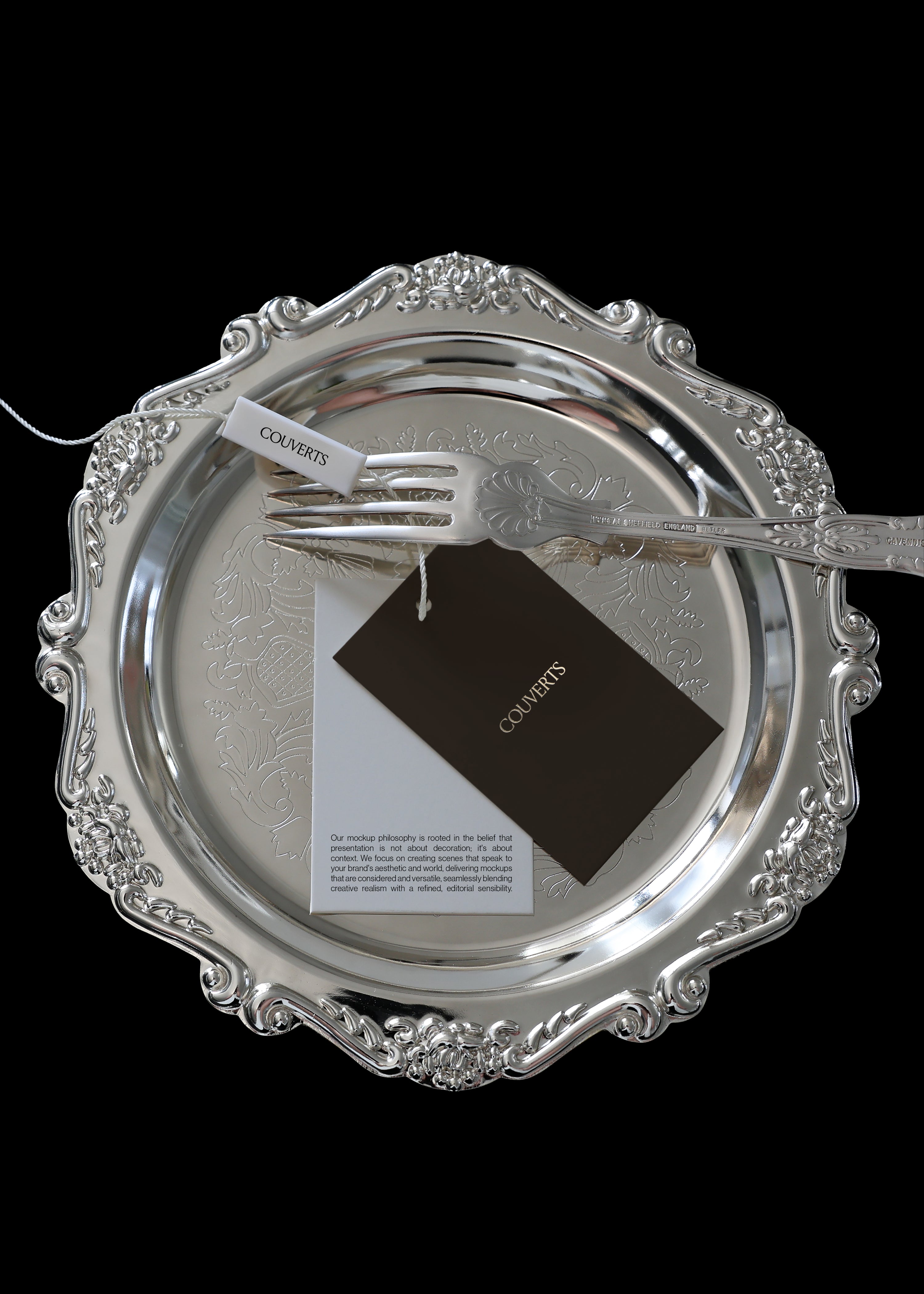 Two swing tag mockups, one dark brown and one white, tied with cord on a silver plate, top-down view
