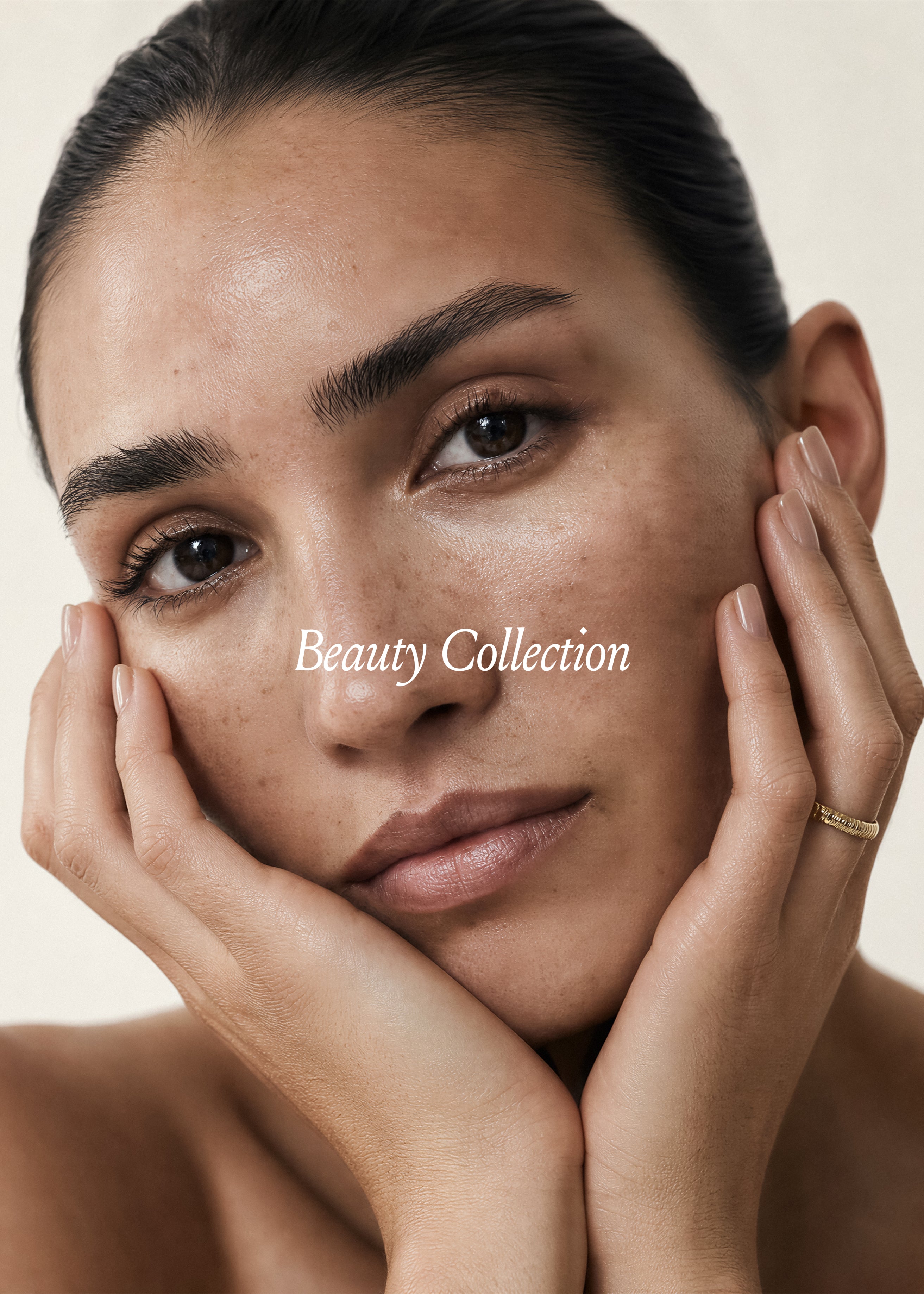 Close-up editorial beauty portrait, woman cradling face in hands, natural skin texture, warm cream background, Beauty Vol. II Studio Blanche