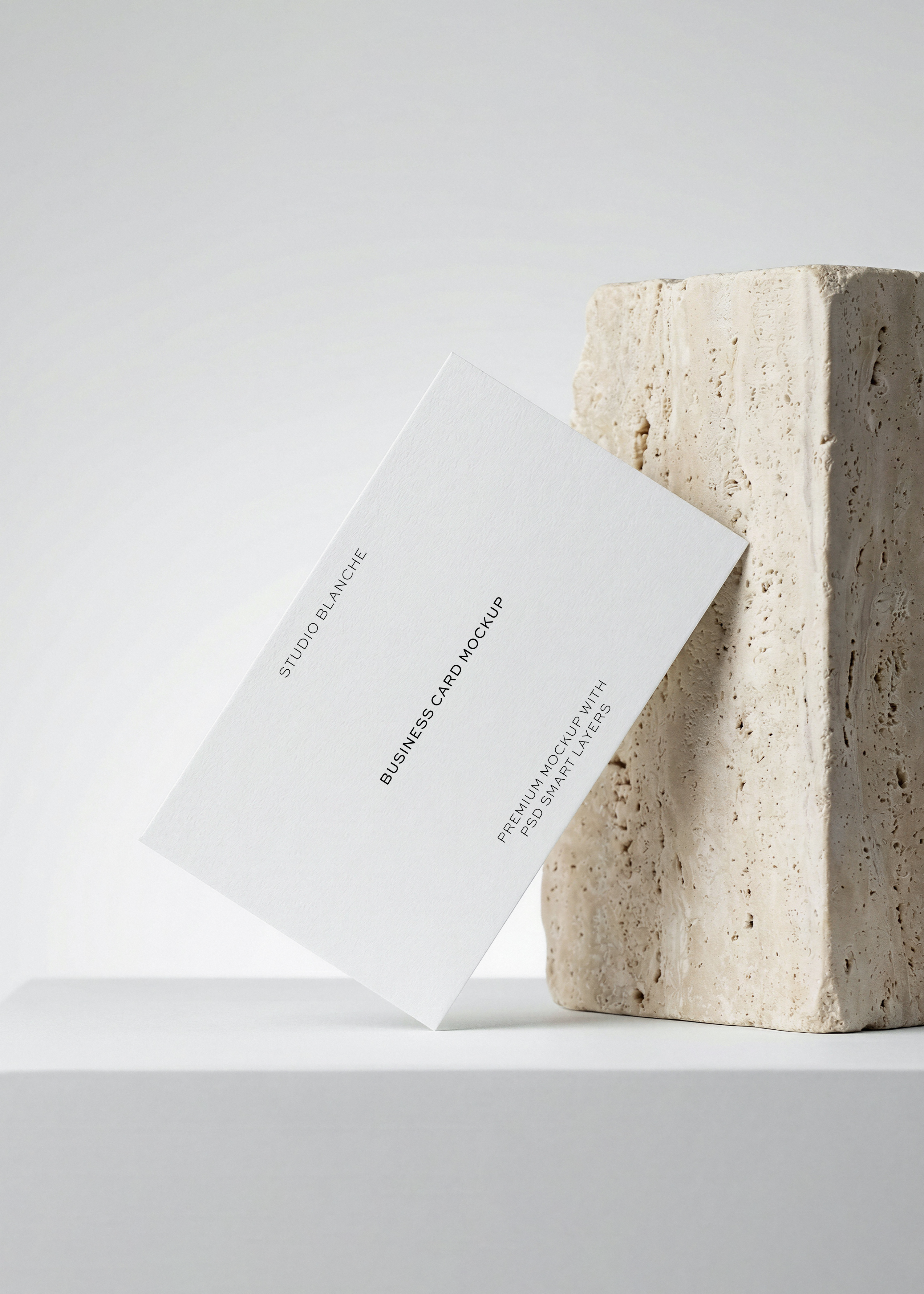 Free business card mockup leaning against travertine stone, with blind emboss and deboss effects, from Studio Blanche
