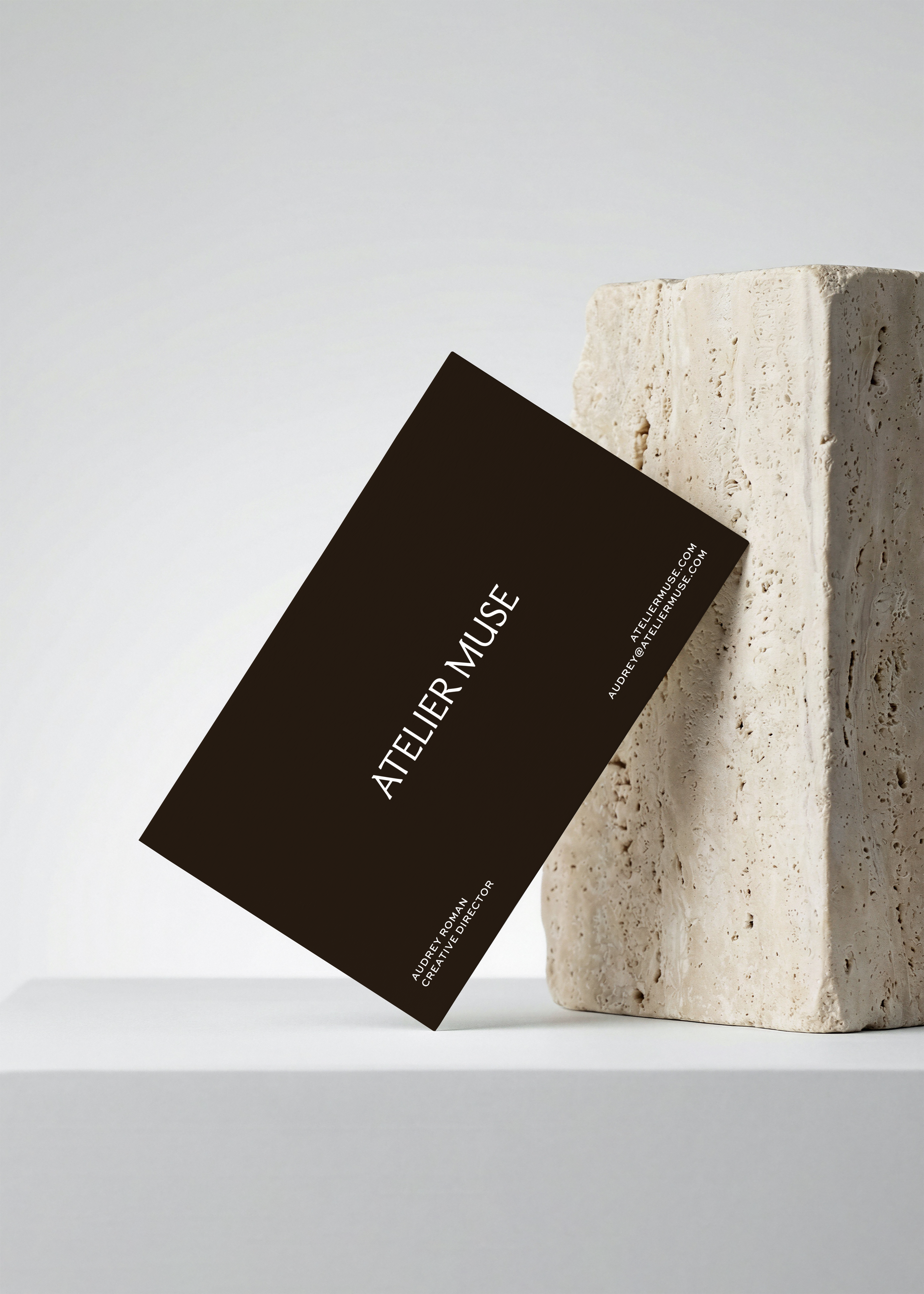 Free business card mockup leaning against travertine stone, with blind emboss and deboss effects, from Studio Blanche