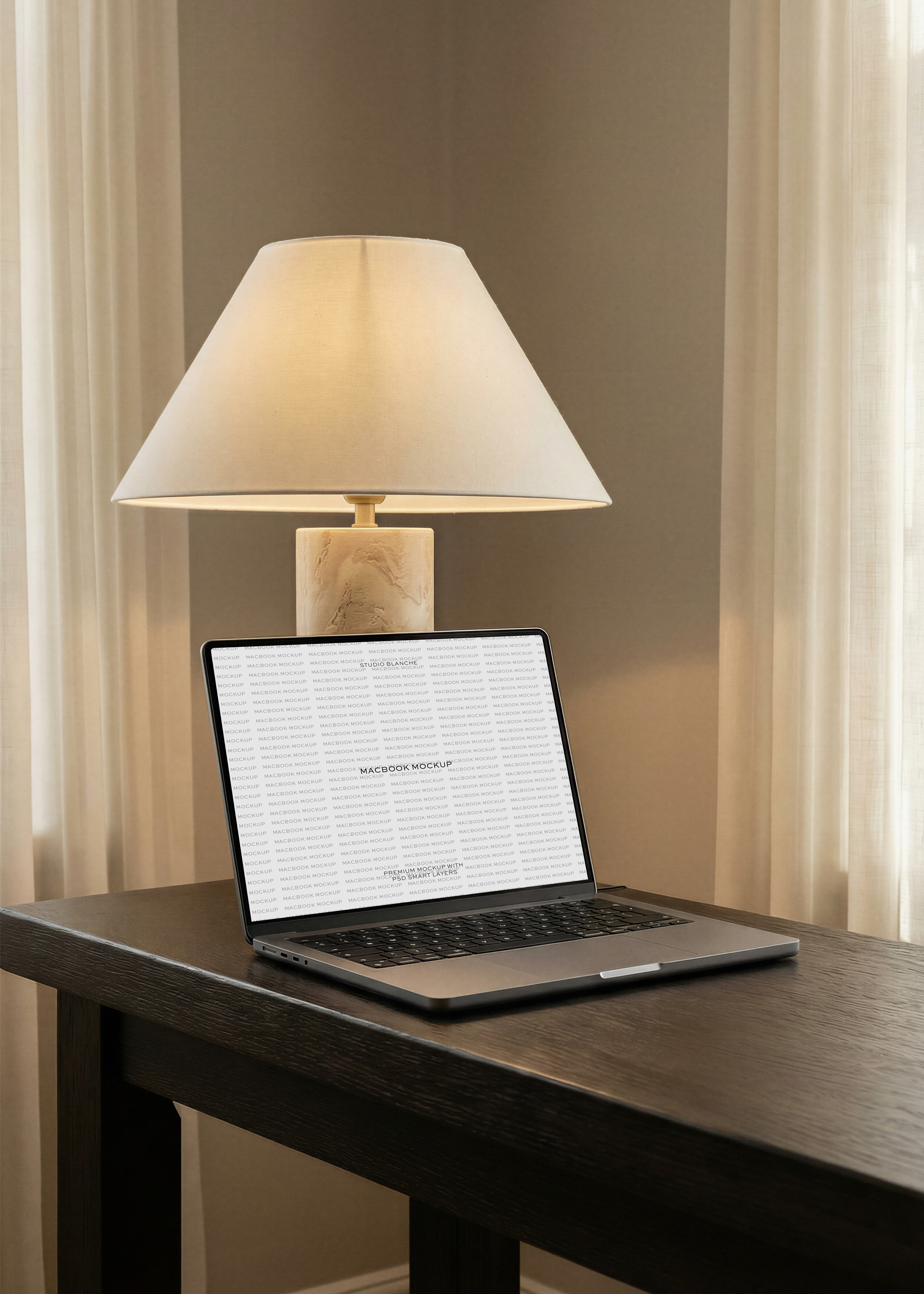 Free MacBook mockup on a dark wood desk with warm lamp light, from Studio Blanche