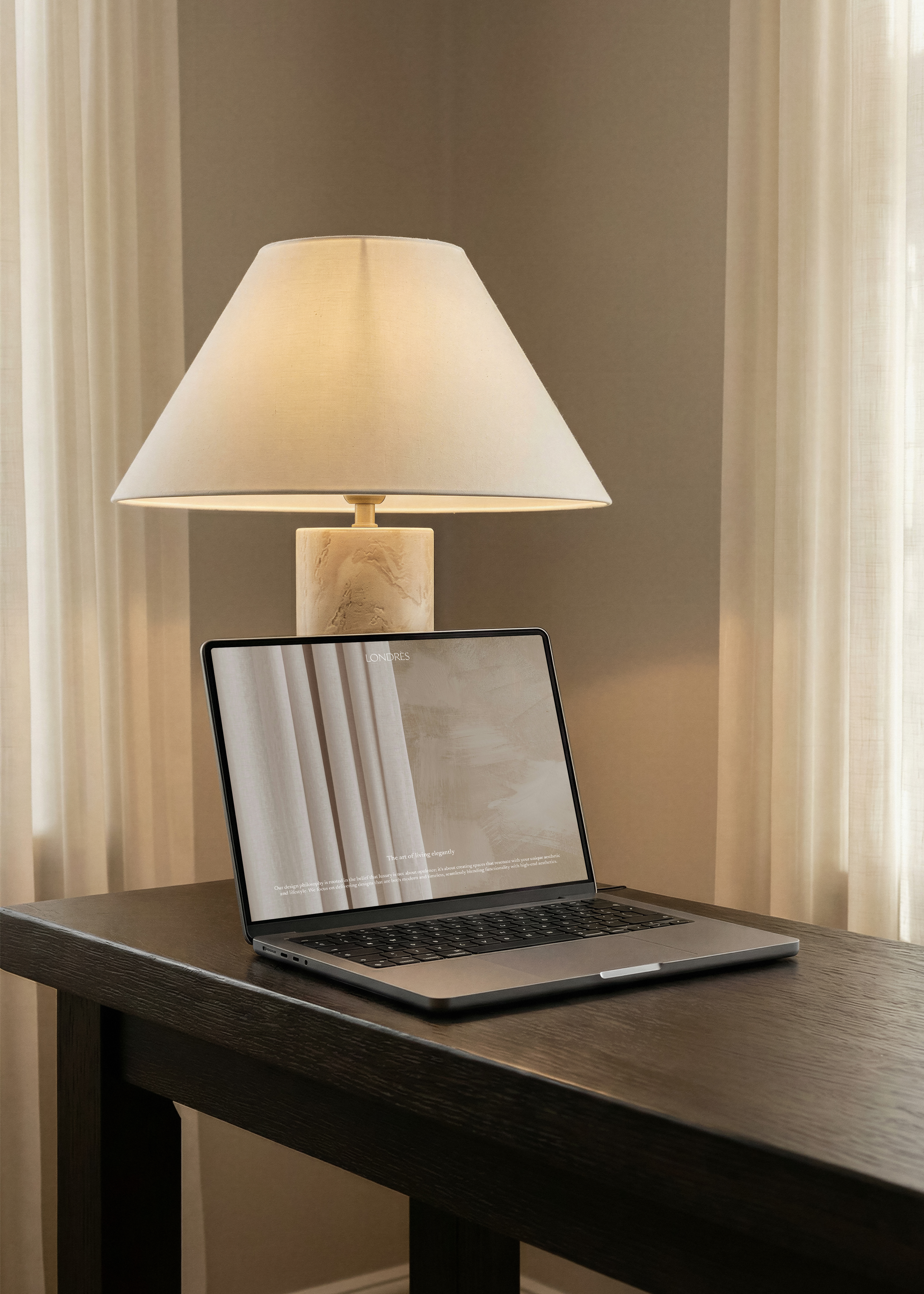 Free MacBook mockup on a dark wood desk with warm lamp light, from Studio Blanche