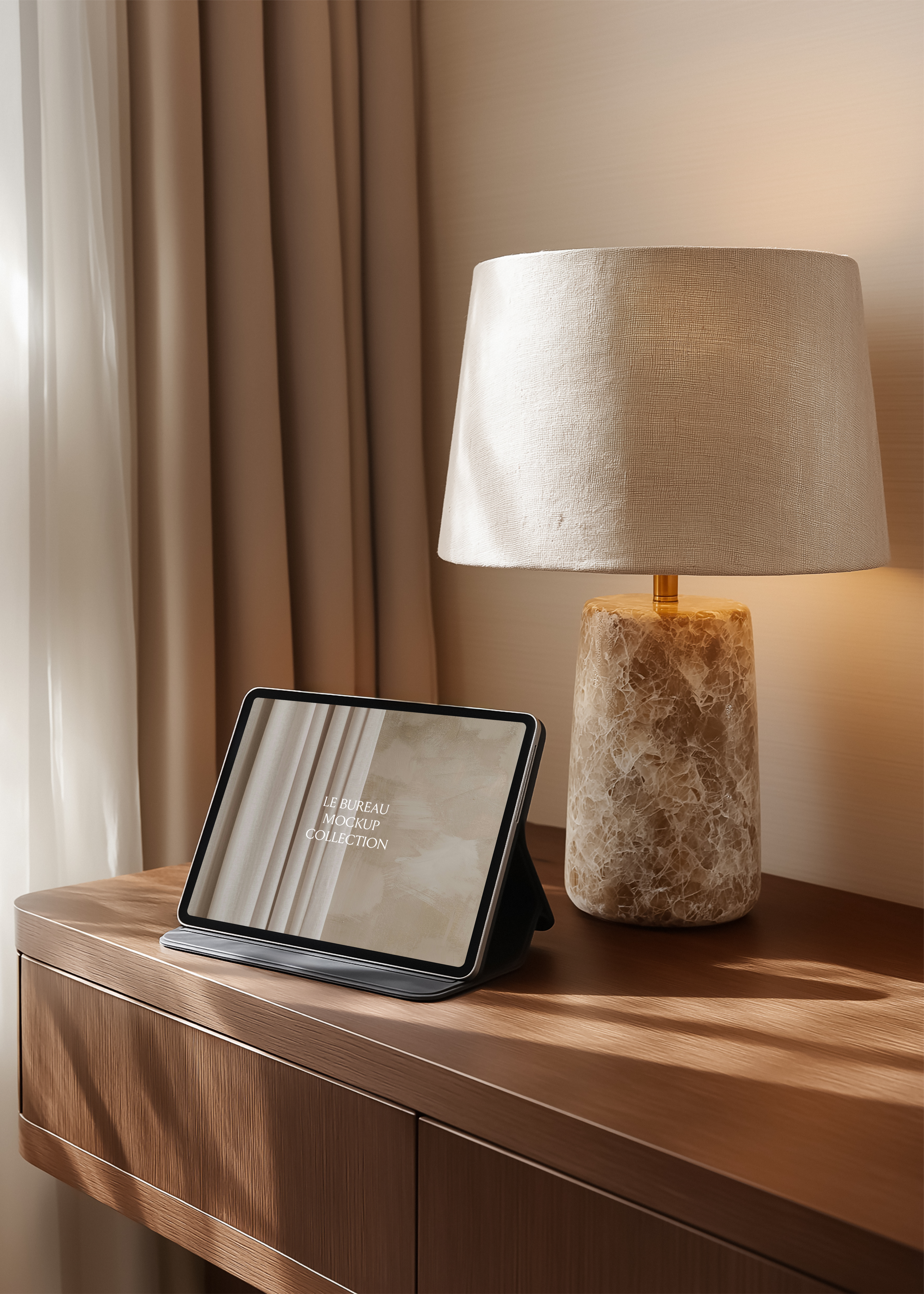 iPad mockup displaying Le Bureau collection branding on warm oak desk, linen lamp shade and draped curtain background