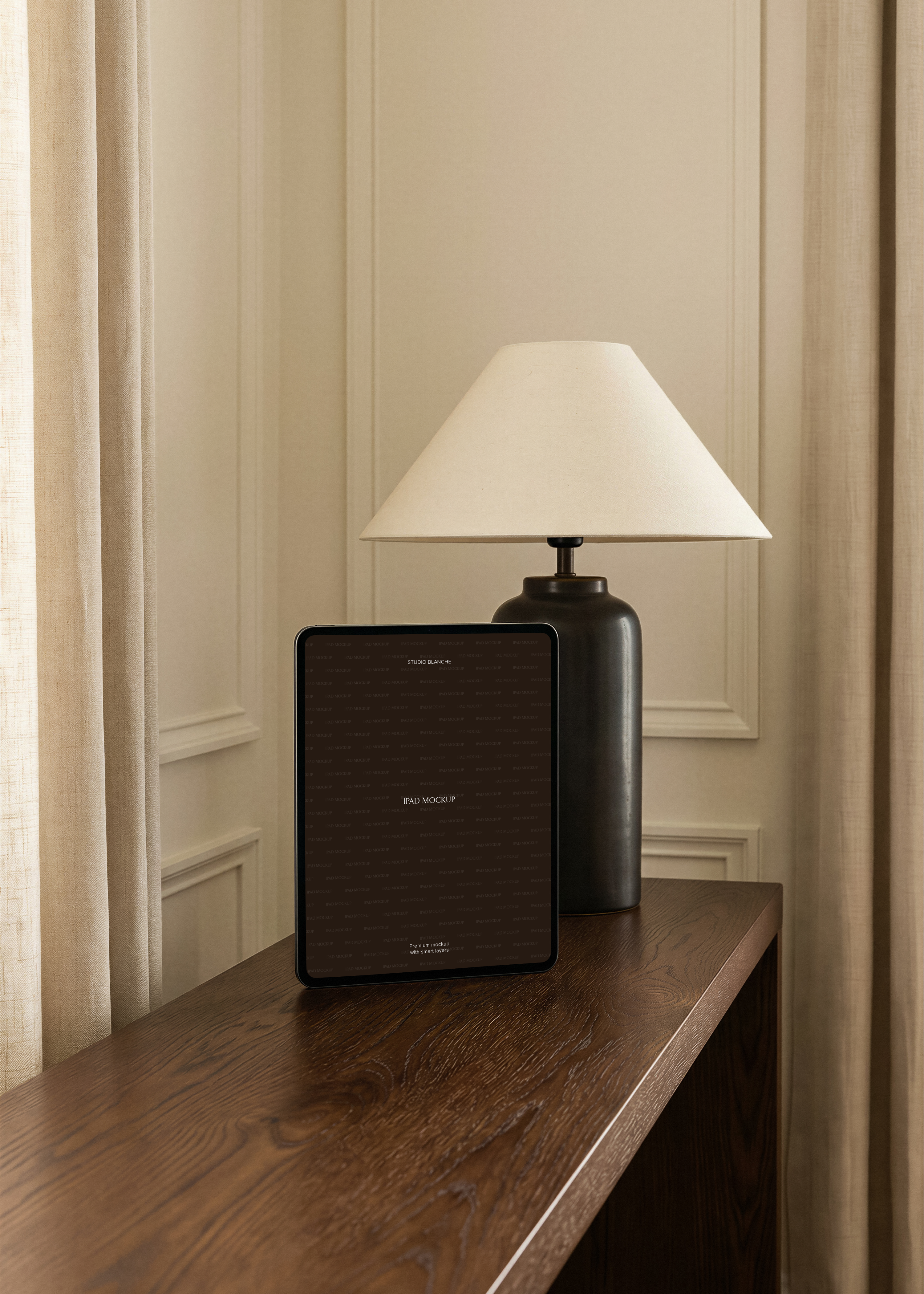 iPad mockup in portrait on dark oak console beside matte charcoal lamp with wide cream shade, panelled wall interior