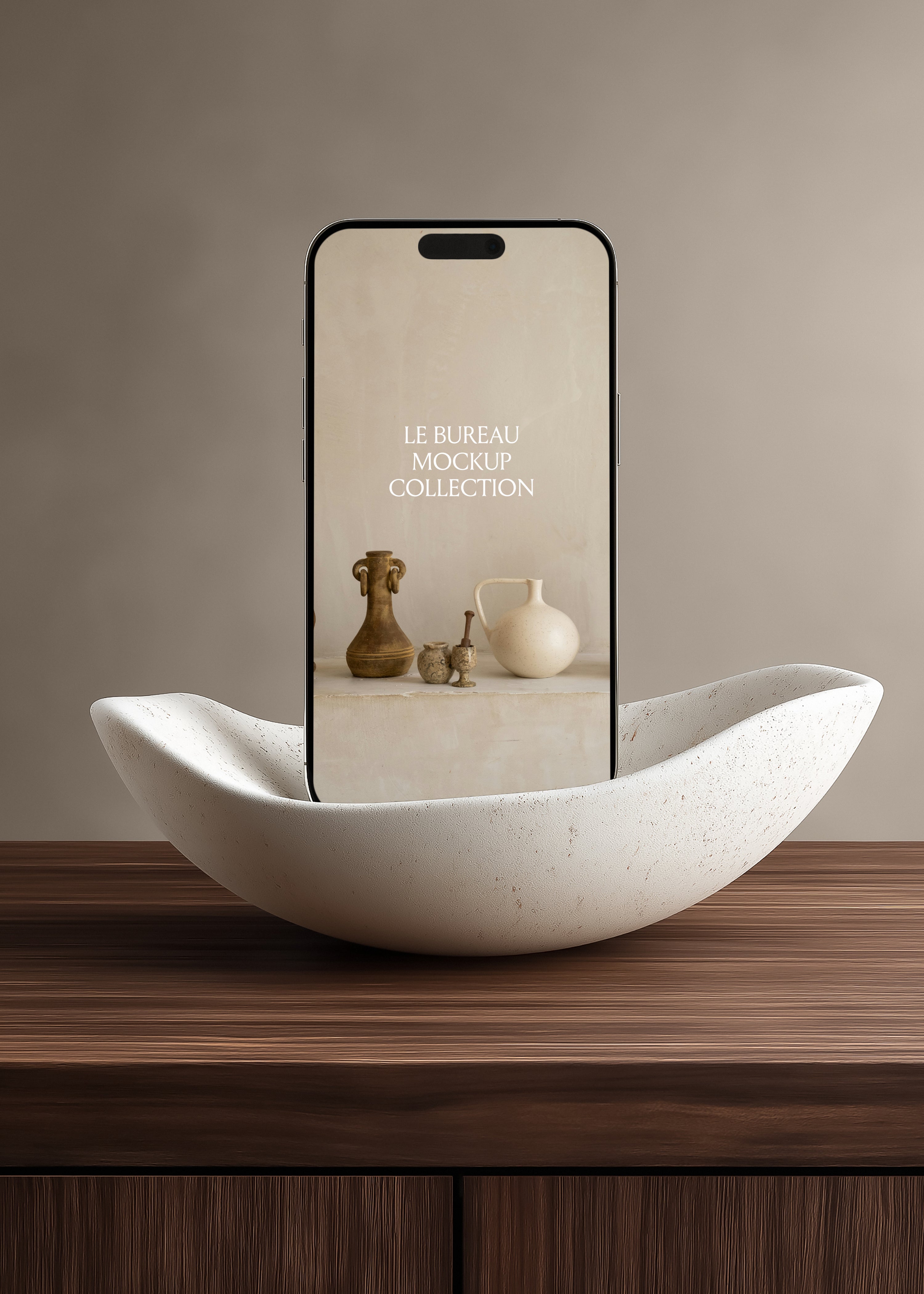 iPhone mockup displaying Le Bureau editorial in travertine bowl on dark oak surface, warm greige minimal background