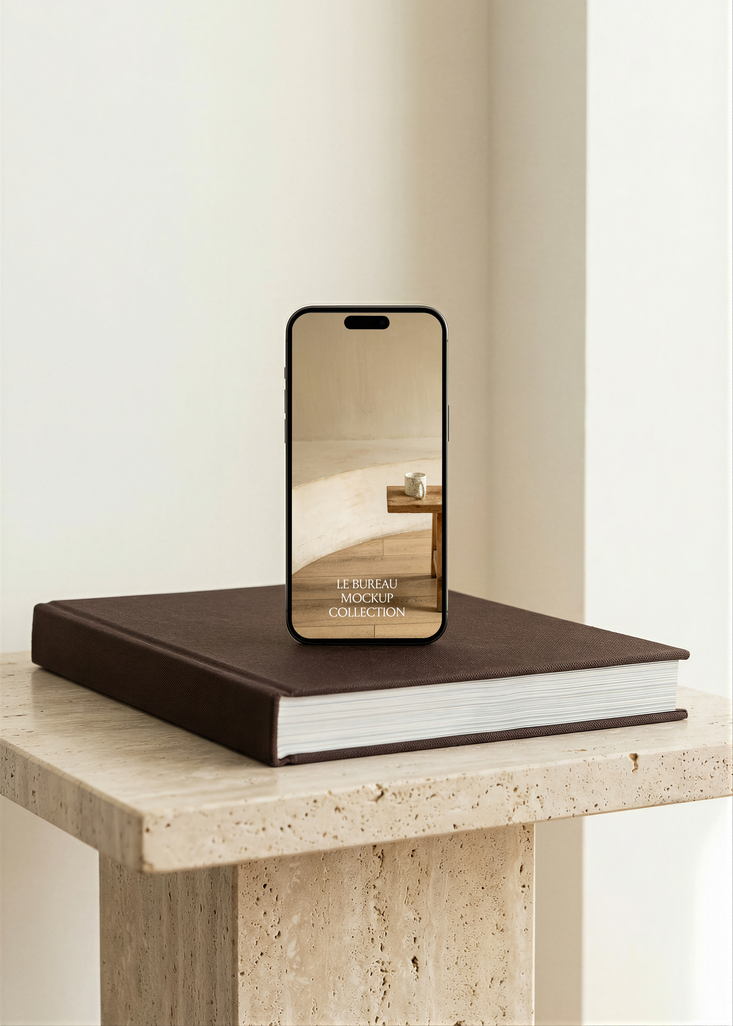 iPhone mockup displaying Le Bureau editorial on hardcover book and travertine plinth, clean white corner interior