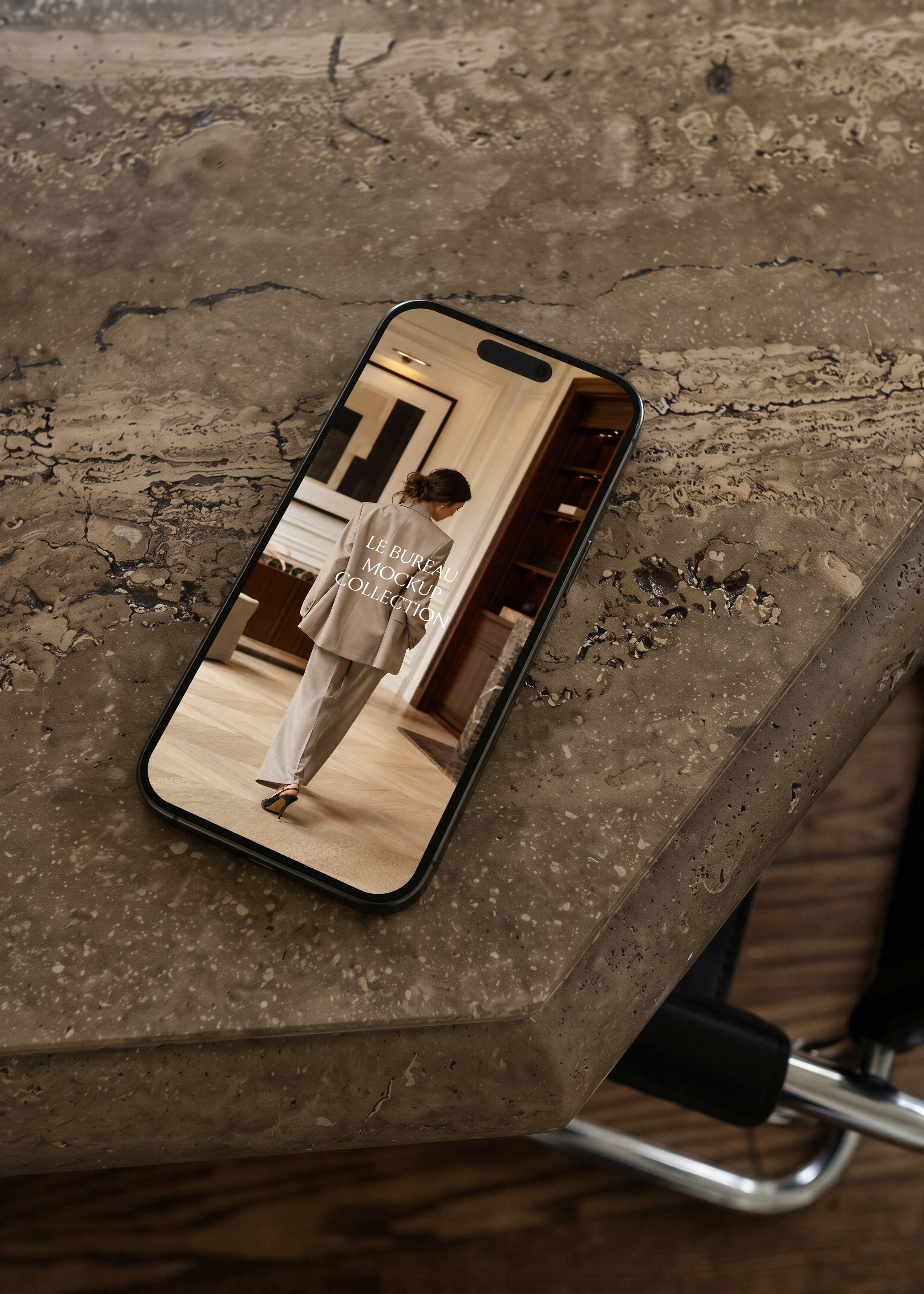 iPhone mockup on travertine surface displaying Le Bureau editorial image, moody warm office scene
