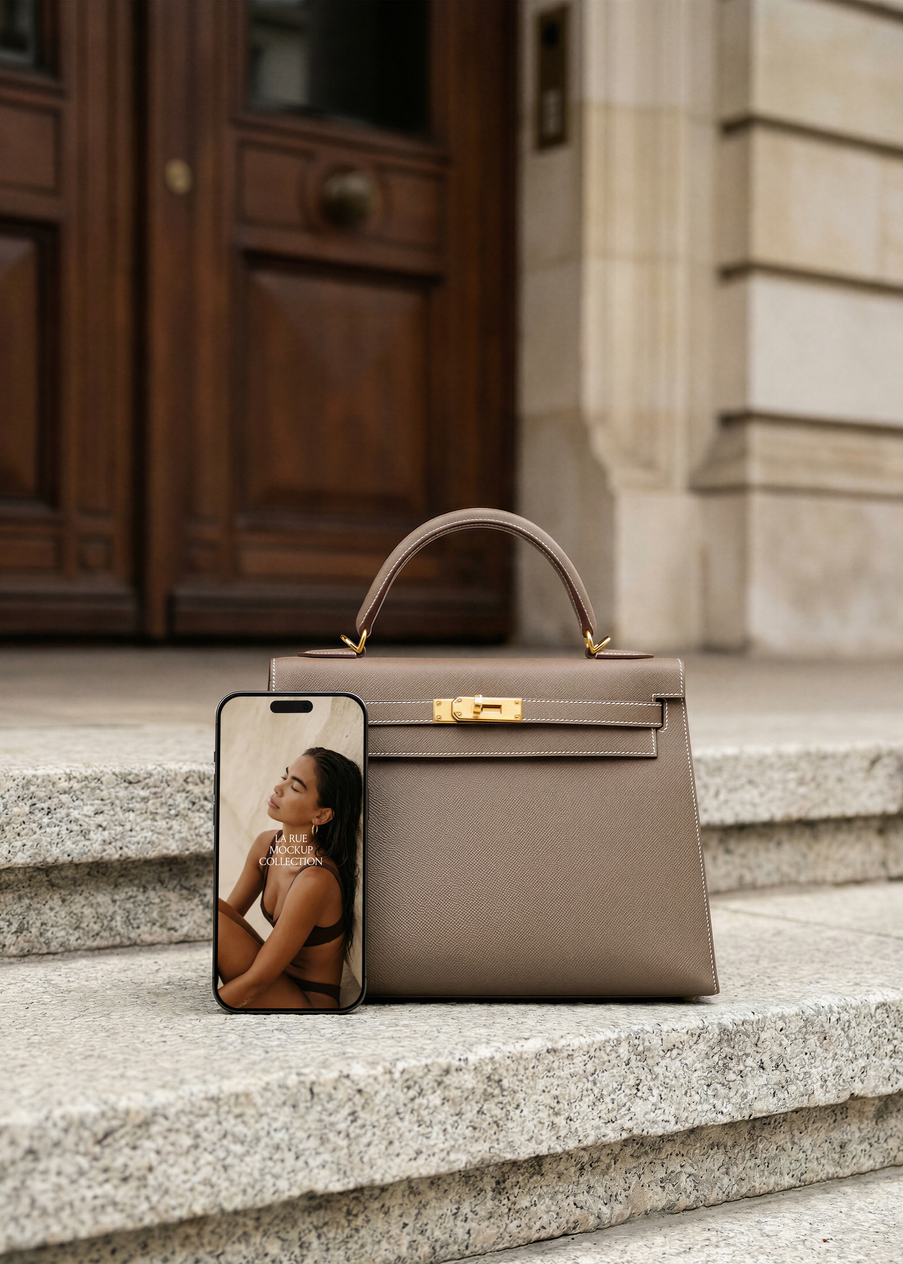 iPhone mockup with luxury brand screen on stone steps beside taupe leather Hermès Kelly handbag, from Studio Blanche