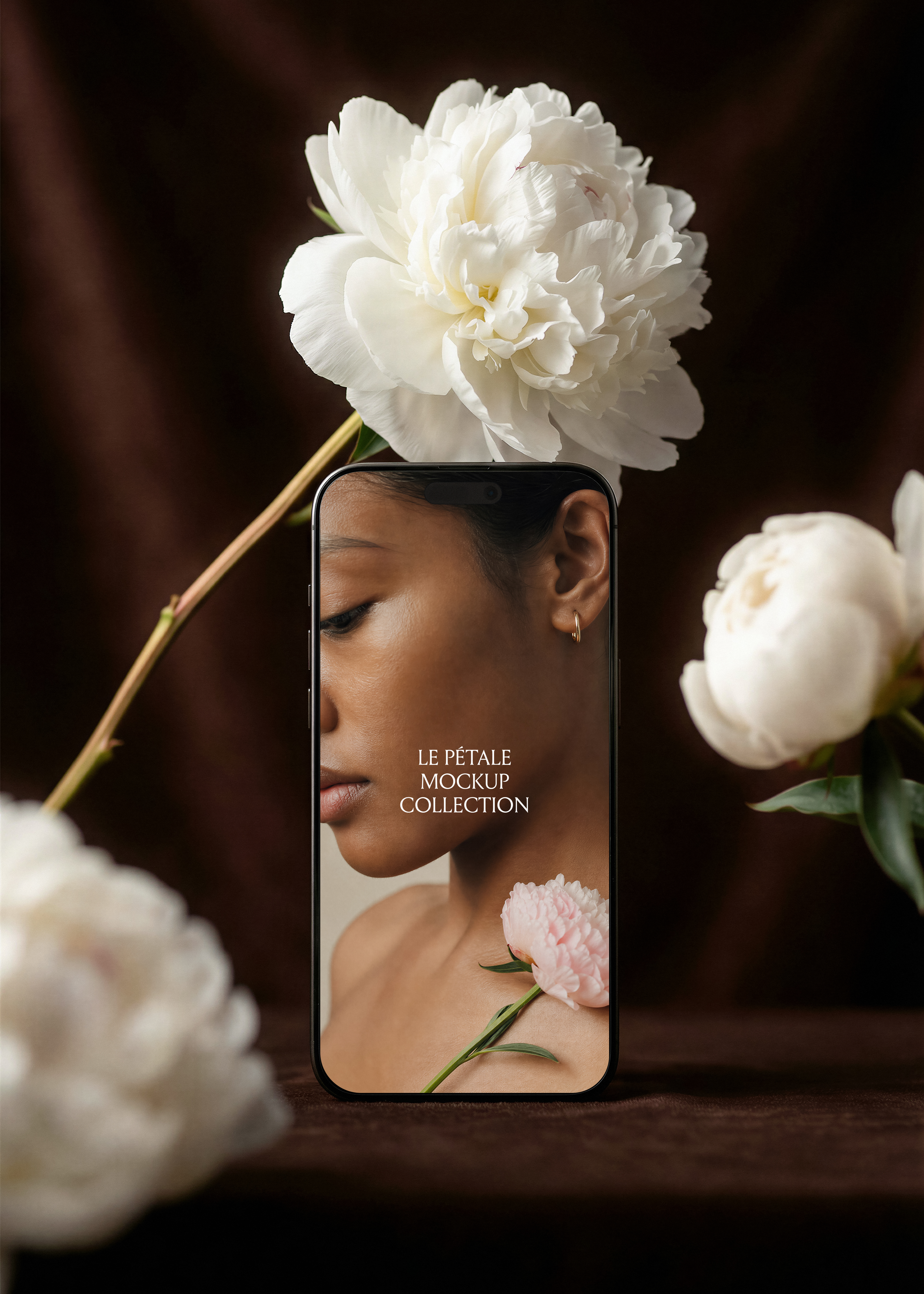 iPhone mockup with beauty campaign screen, white peony overhead, blurred peonies foreground, dark espresso velvet backdrop 