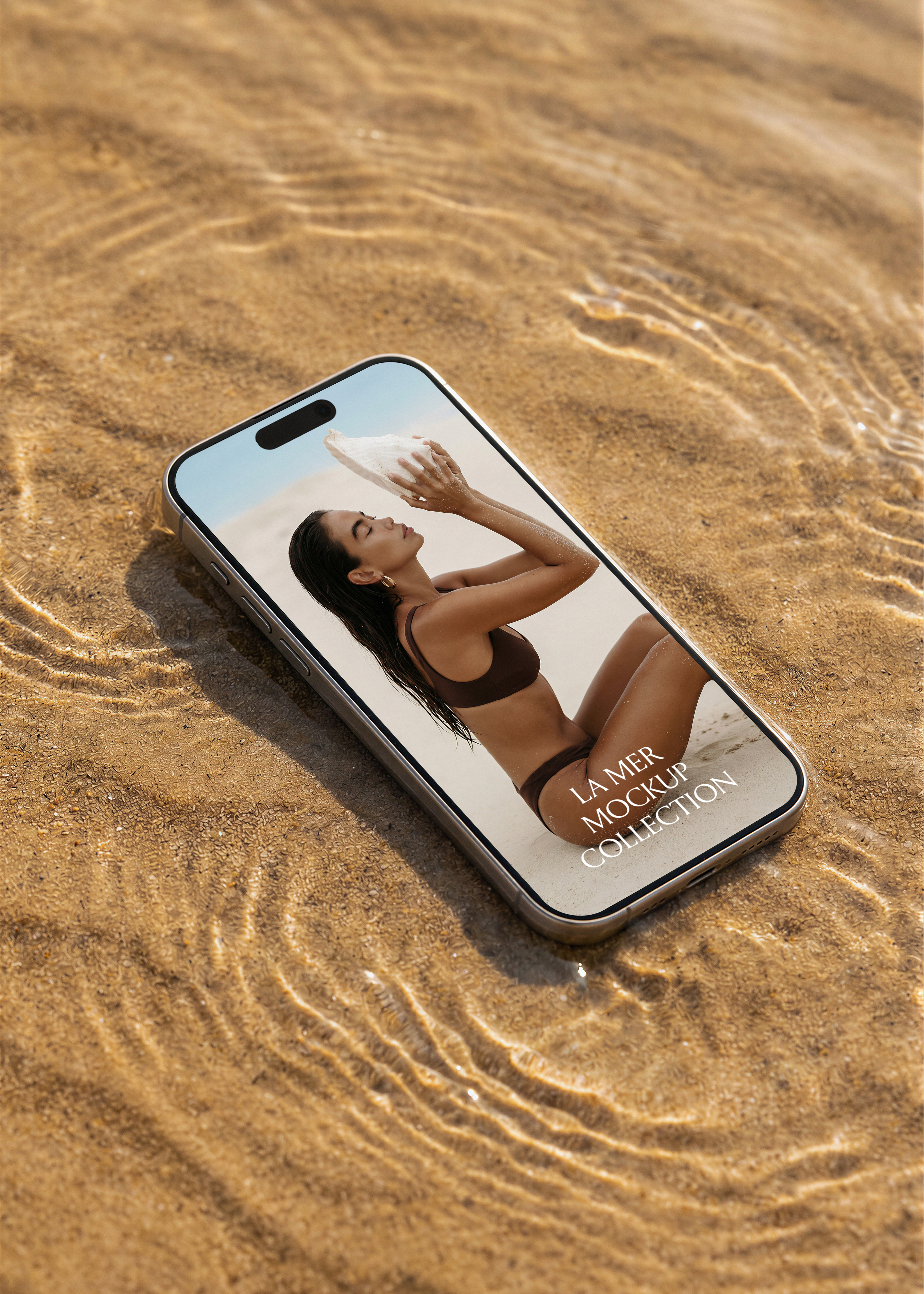 iPhone mockup lying flat on wet rippled sand with shallow water reflections, warm golden light, La Mer collection