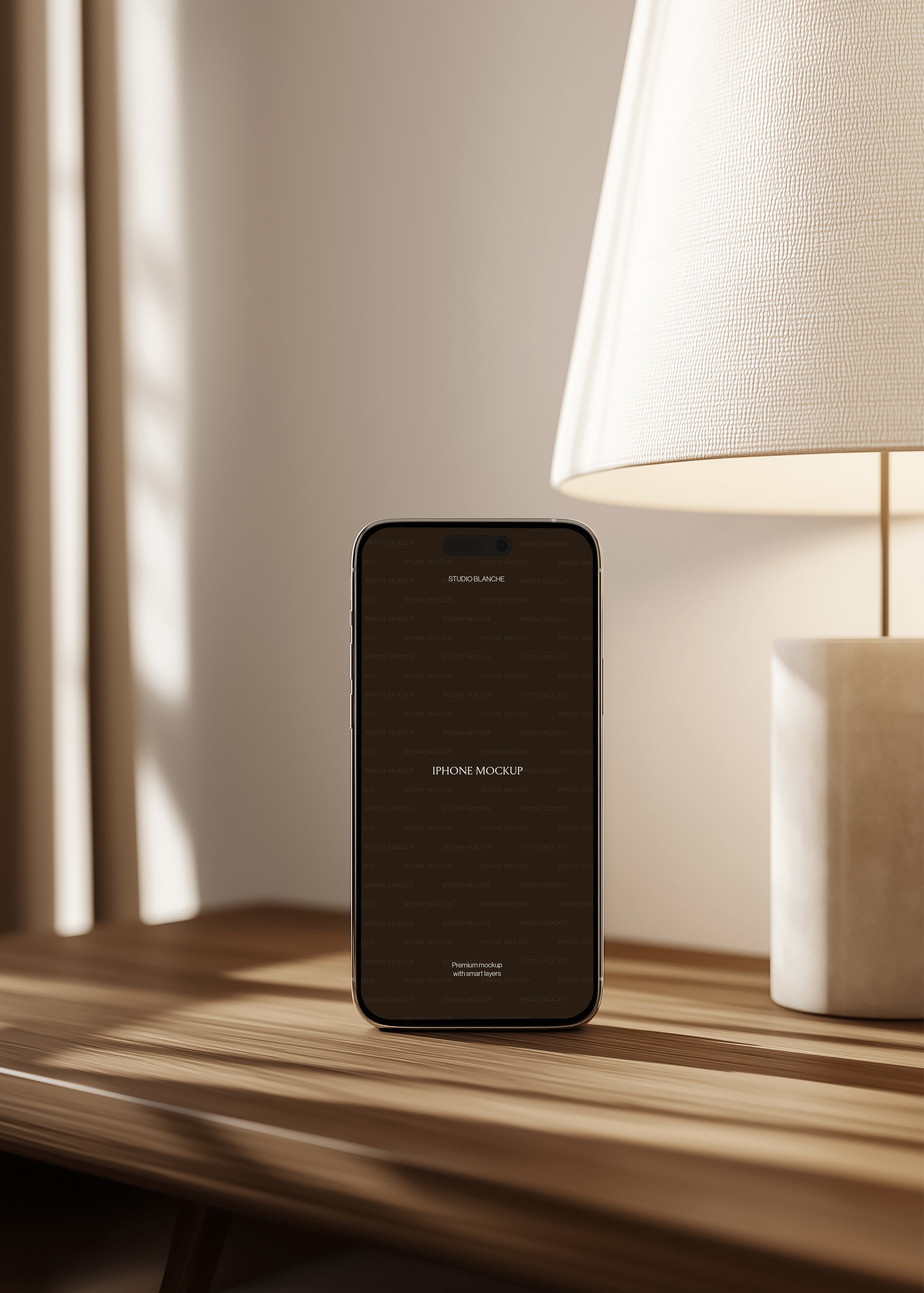 iPhone mockup upright on striped oak surface beside stone-base lamp with wide linen shade, warm dappled light interior