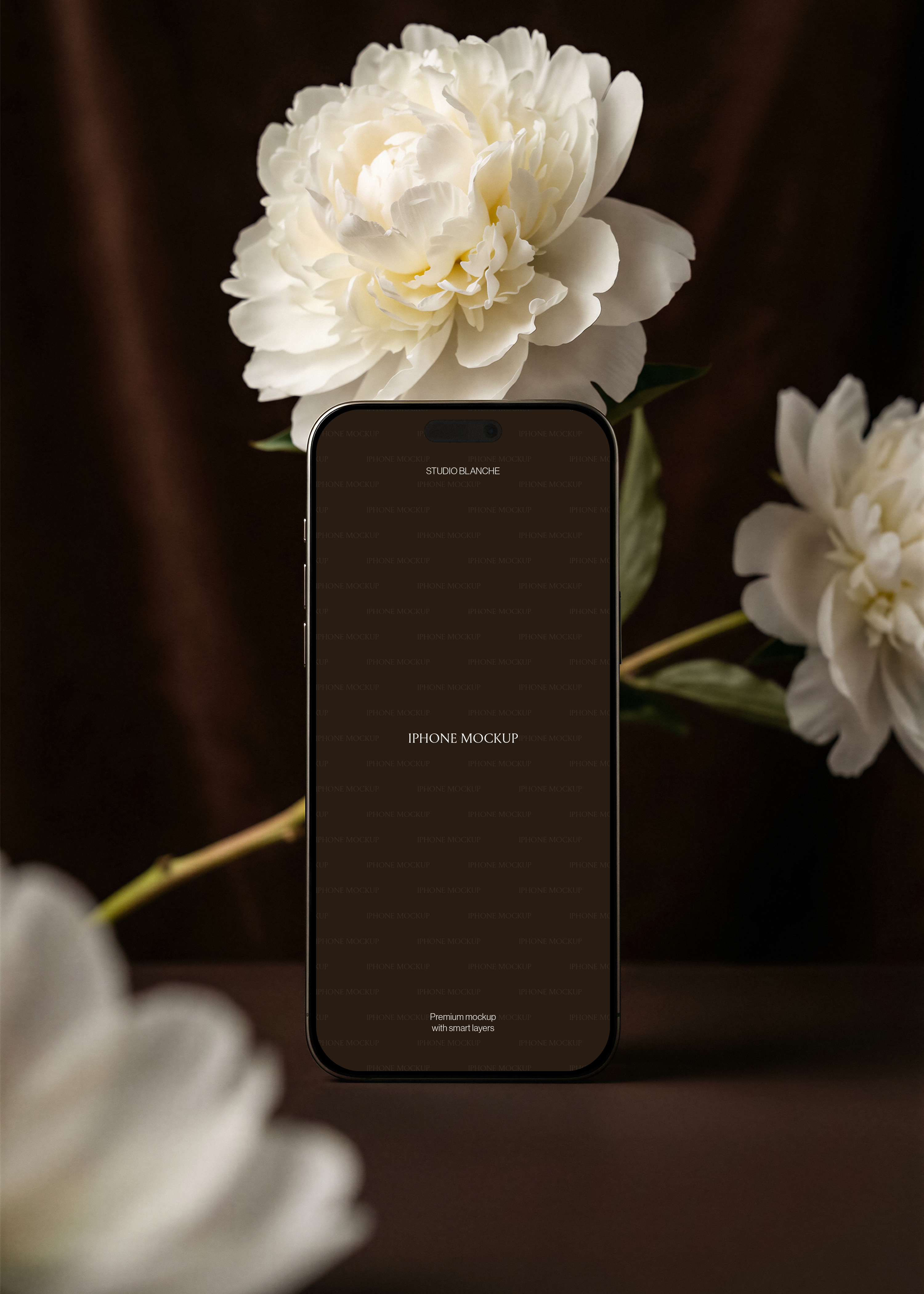 Gold iPhone mockup with screen area, white peony overhead, second bloom right, blurred foreground peony, dark velvet background