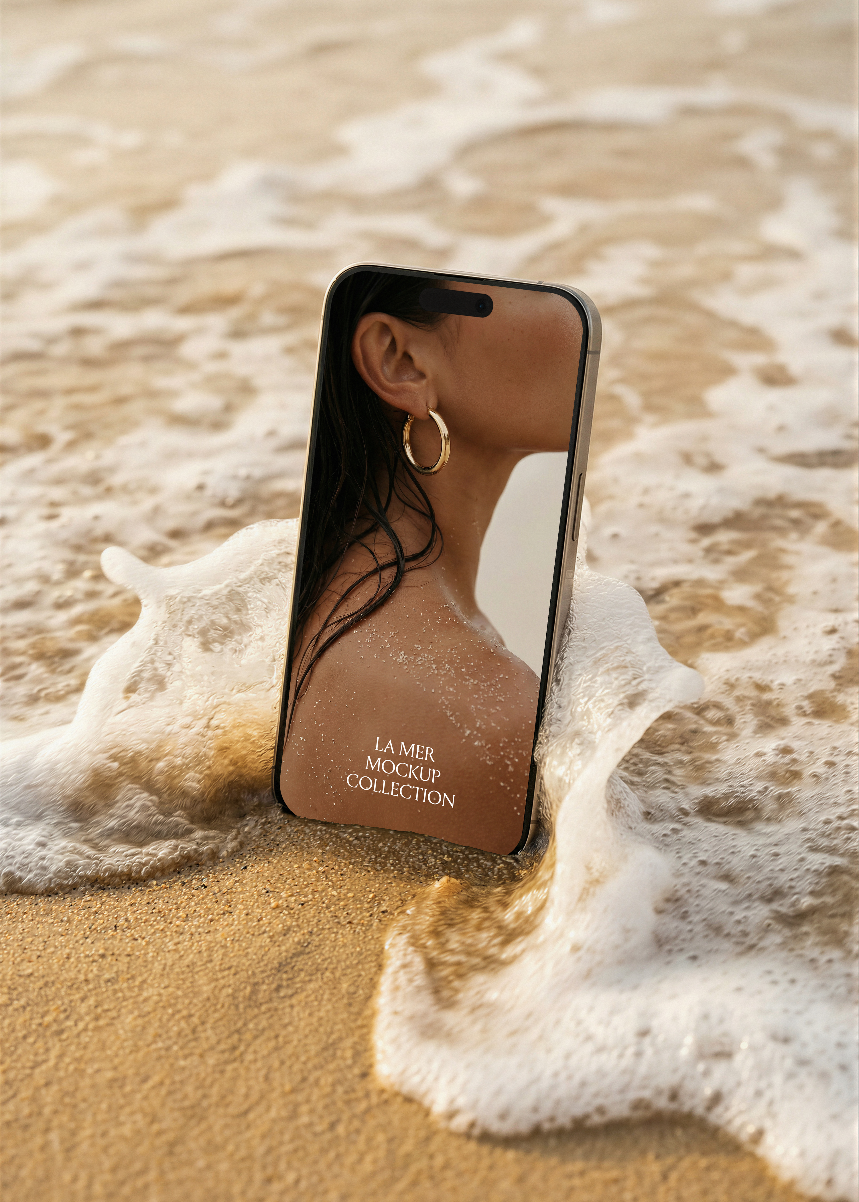 iPhone mockup on sandy shore with breaking wave foam, example screen showing editorial beauty campaign image