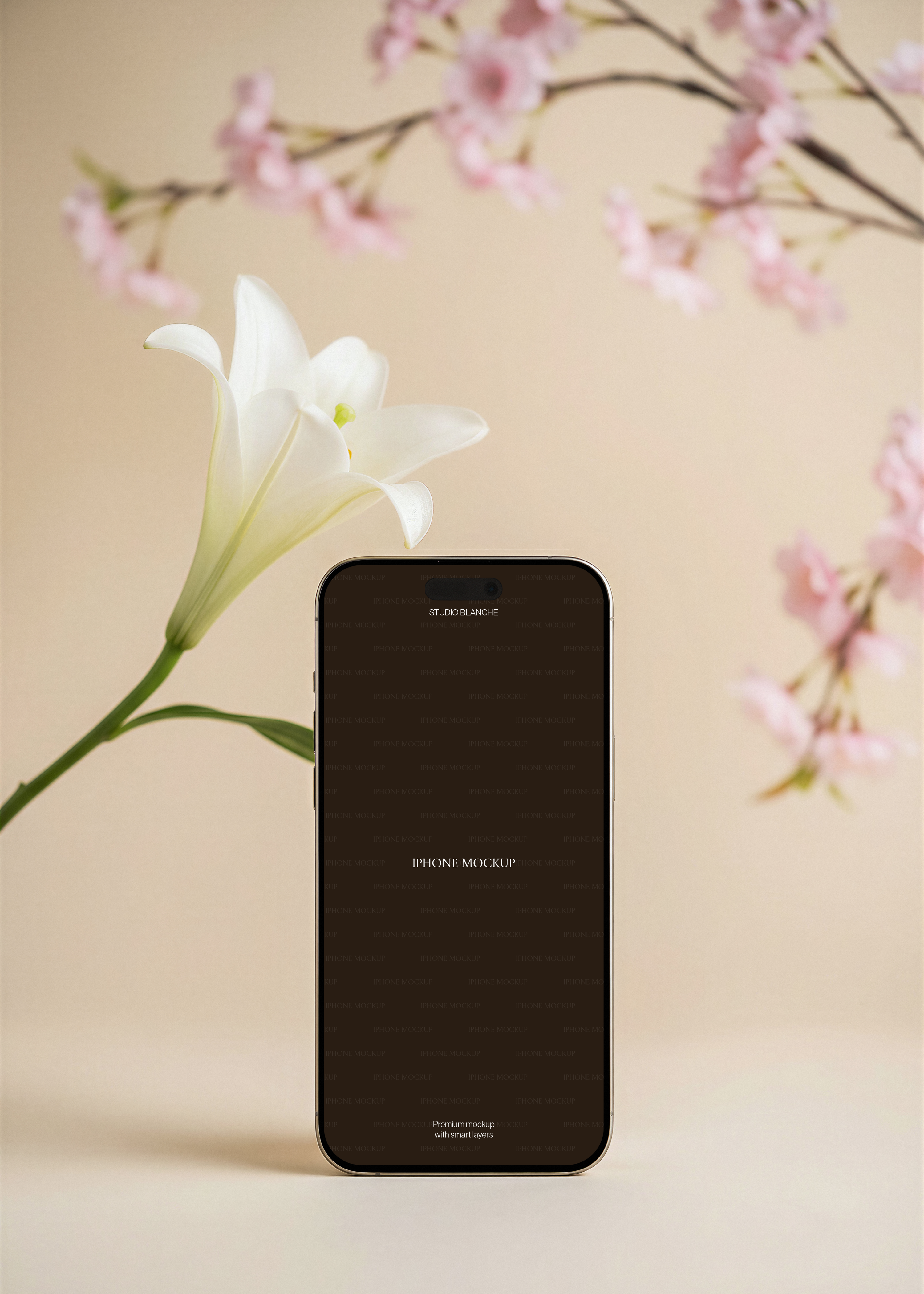 Gold iPhone mockup showing screen area, open white lily beside device, pink cherry blossom branches arcing background, beige surface