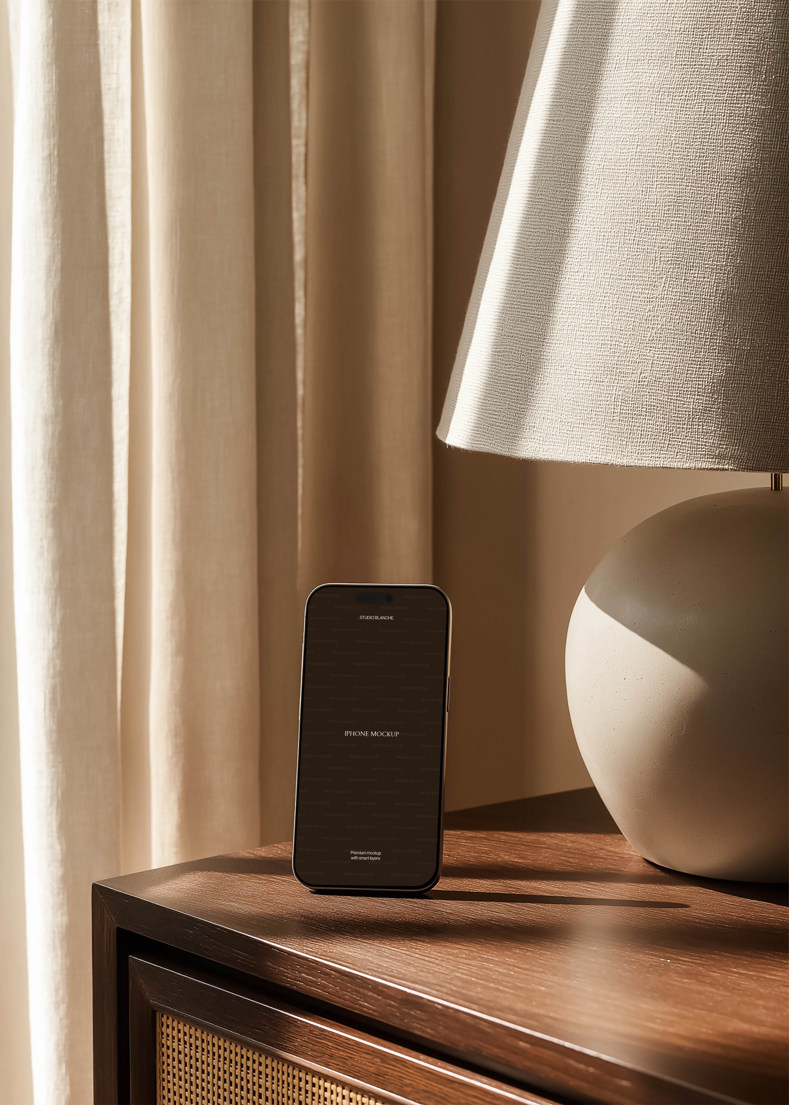iPhone mockup upright on dark oak rattan cabinet beside matte clay sphere lamp with wide linen shade, warm curtain backdrop