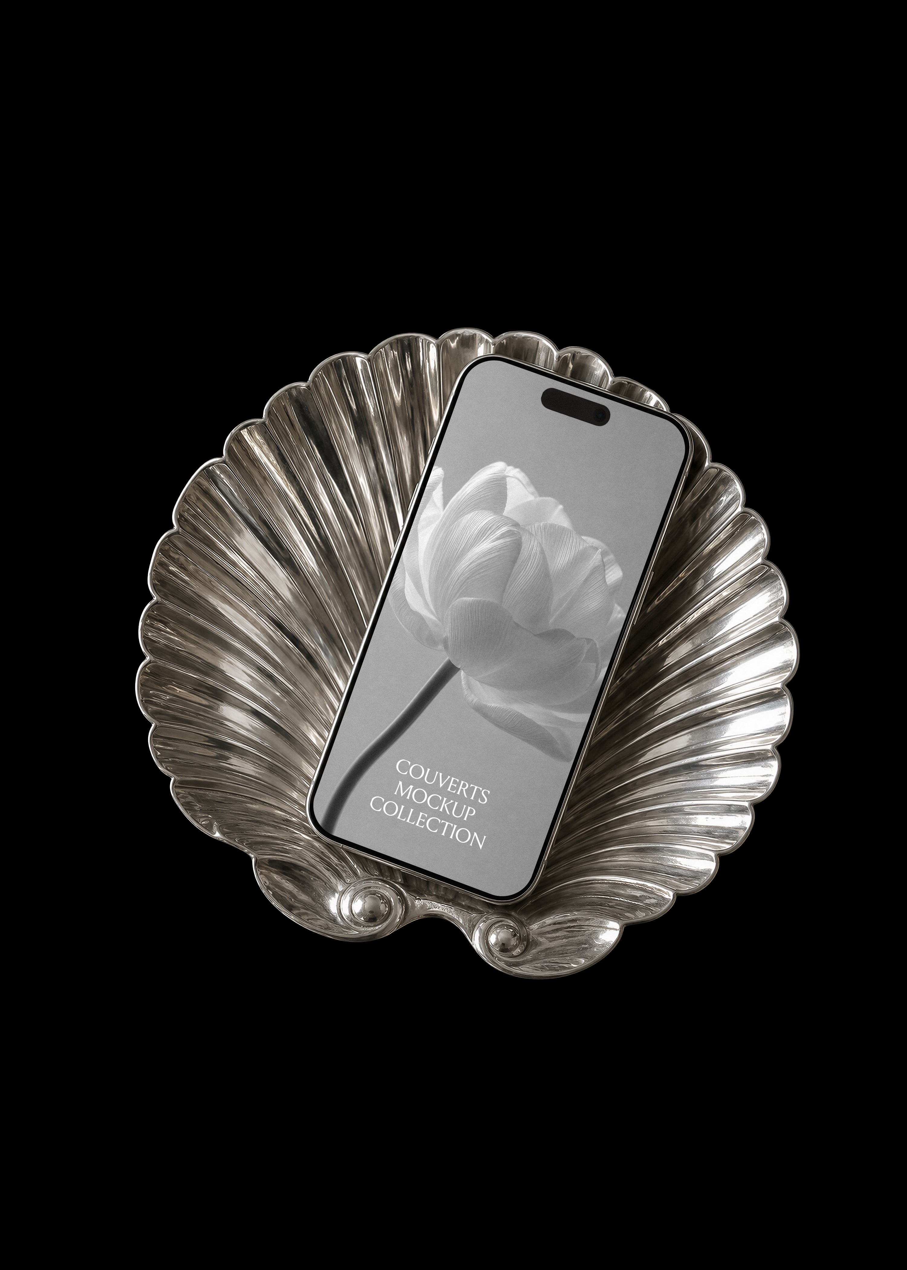 iPhone mockup with black and white floral screen resting on a fluted silver scallop shell tray on black backdrop
