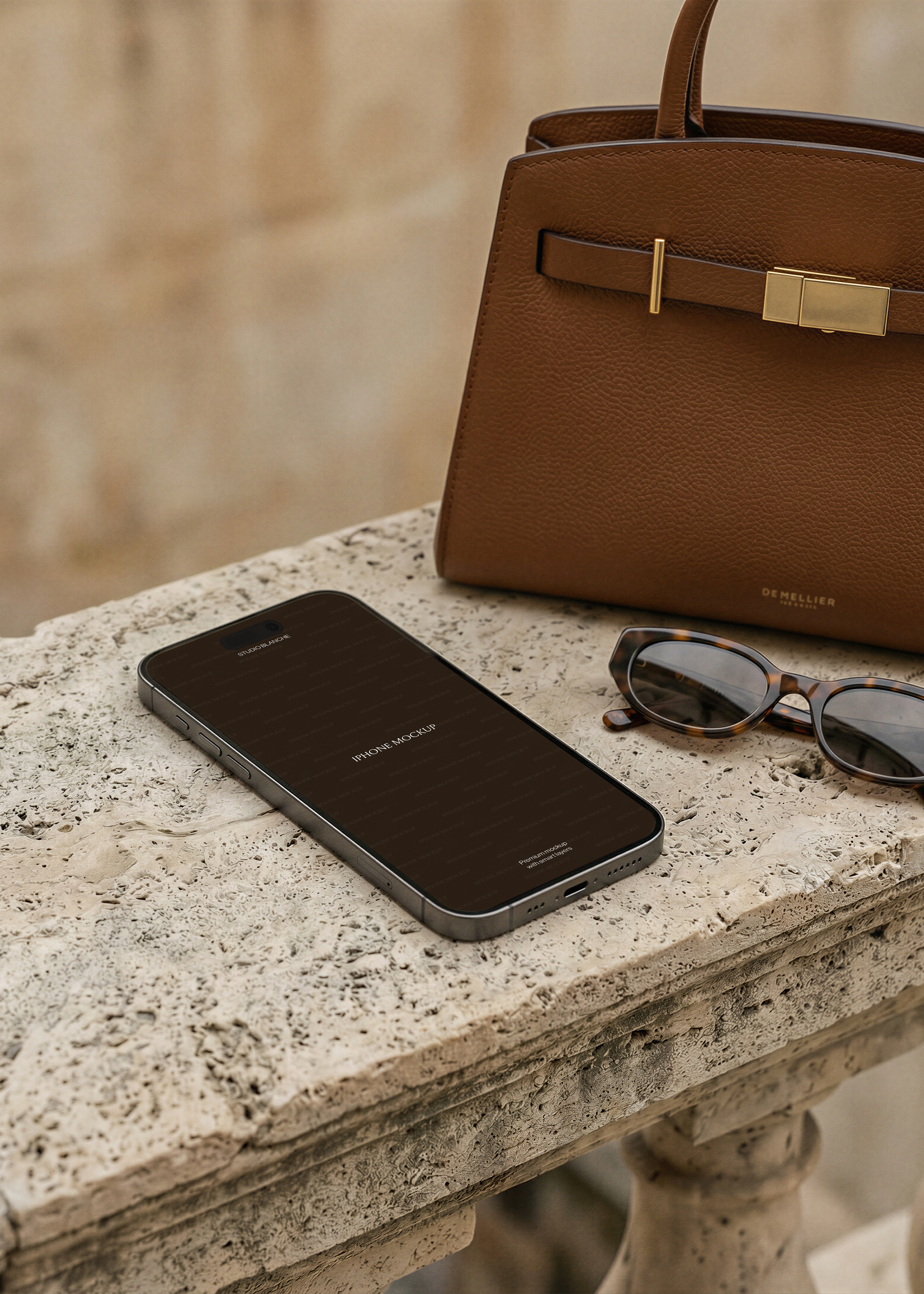 iPhone mockup flatlay on stone surface with tan leather handbag and sunglasses, dark placeholder screen, warm tones