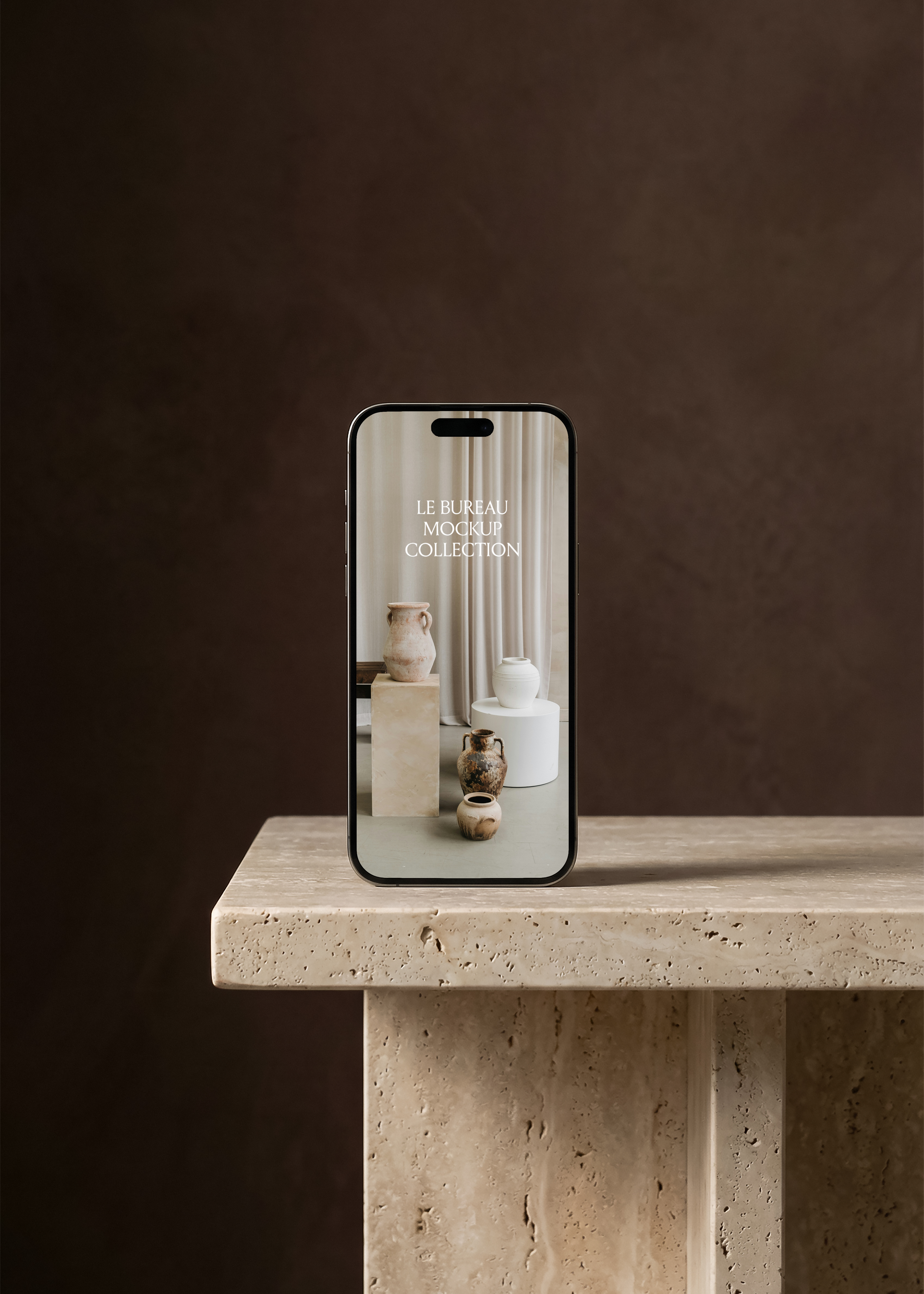 iPhone mockup standing on travertine stone bench against dark brown wall, screen showing ceramic vase still life